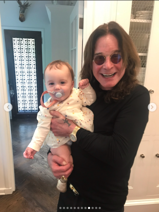 Ozzy Osbourne holds one of his grandchildren as he smiles at the camera, from a post dated July 24, 2025 | Source: Instagram/lisastelly