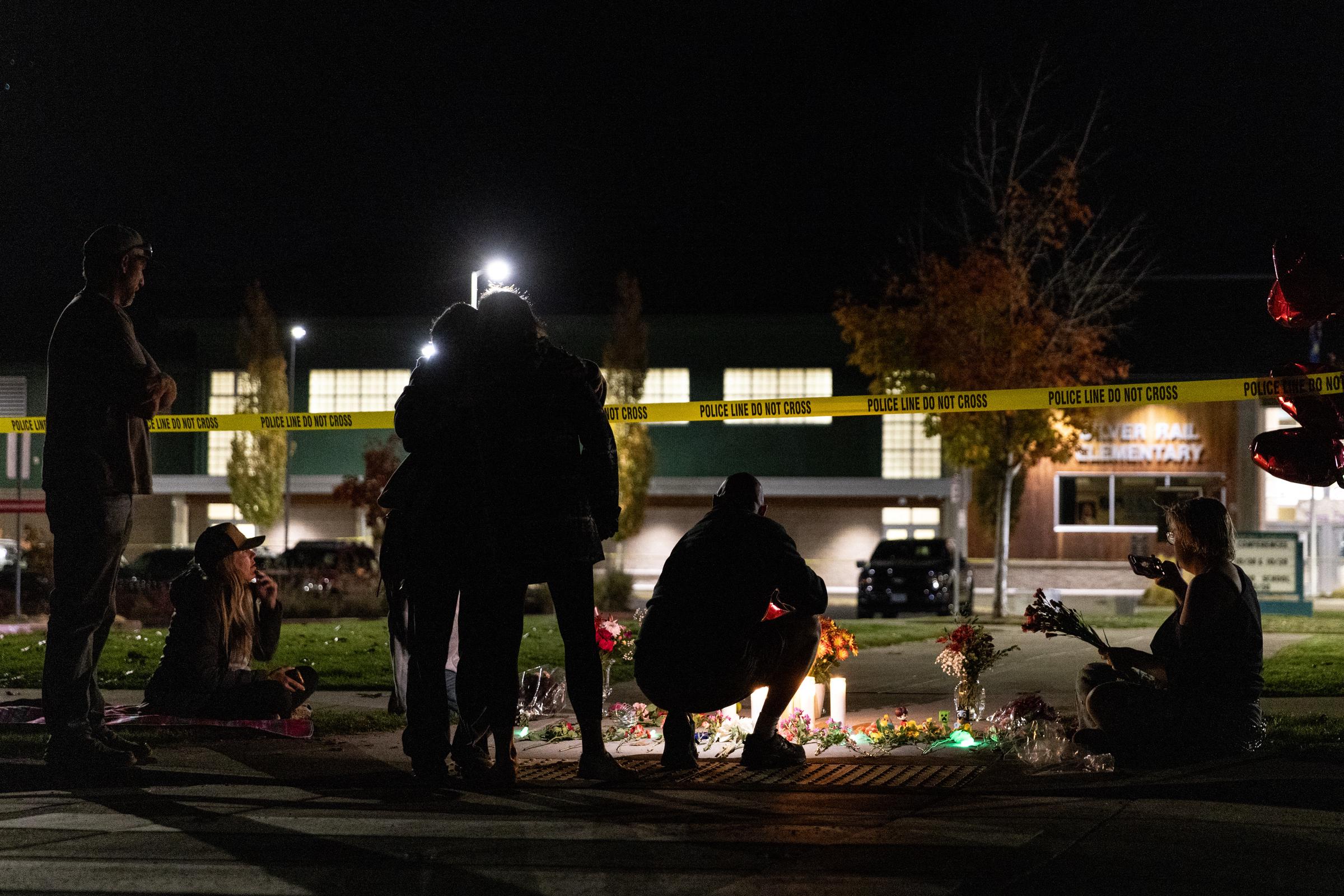 Community members gather beside a candlelit memorial outside Silver Rail Elementary School as police tape remains stretched across the property. | Source: Getty Images