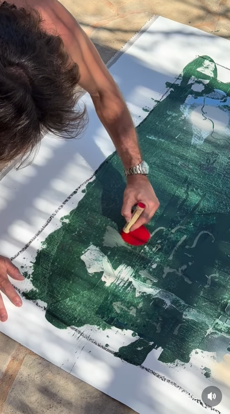 Jake Hall works on a large green-toned artwork while painting outdoors. | Source: Instagram/jakehall