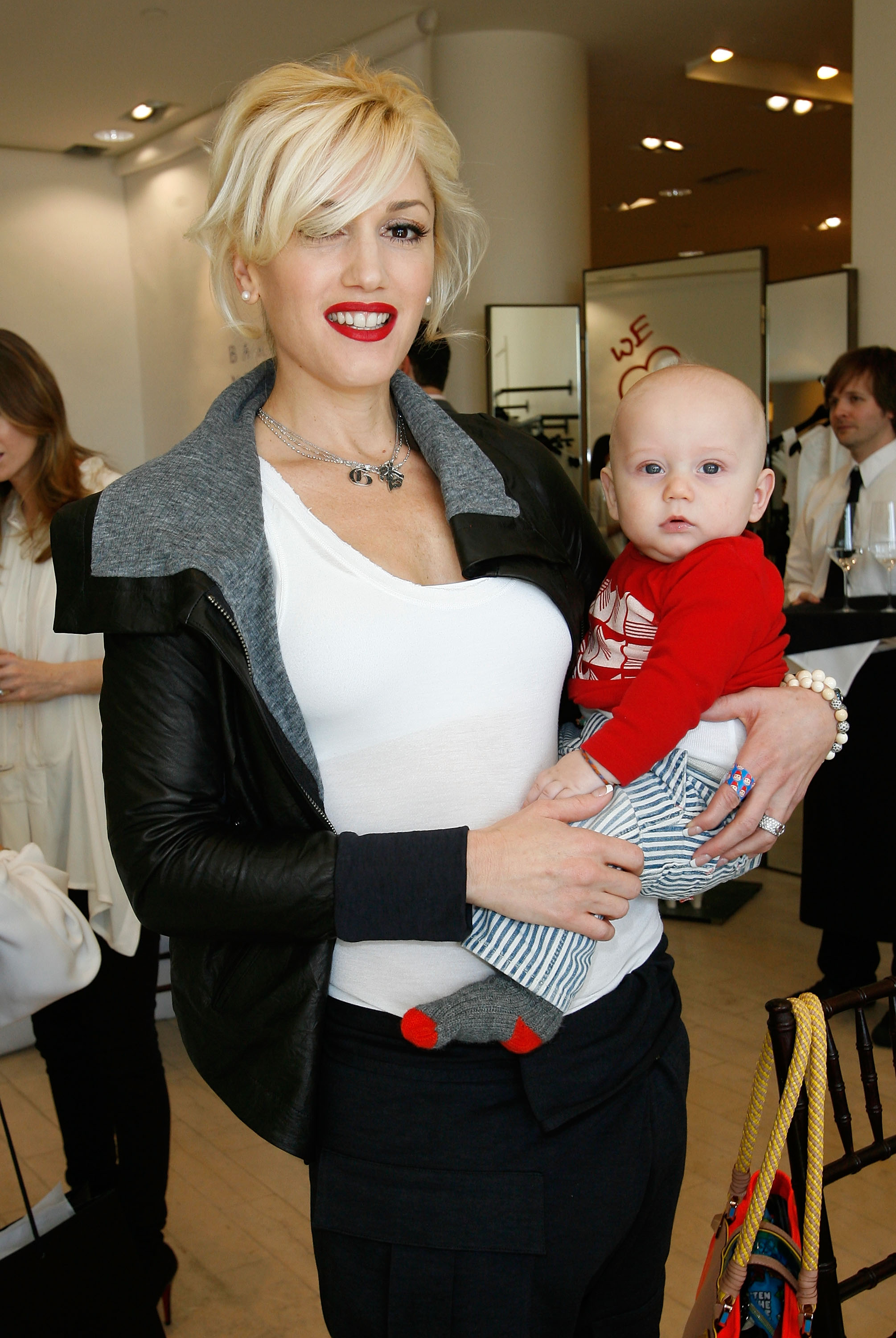 Gwen Stefani smiled as she held her baby son Zuma Rossdale, who looked adorable in a red long-sleeve top and striped pants with a baby bald head. At this event, they attended the celebration for Andrea Lieberman hosted by Barneys New York and Jennifer Lopez on February 18, 2009, in Beverly Hills, California.