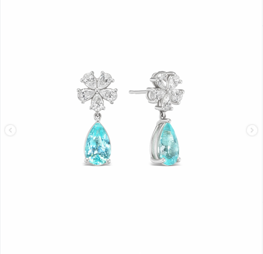 A close-up highlighted Paula’s Paraíba tourmaline drop earrings, featuring vivid blue pear-shaped stones suspended beneath diamond floral details. | Source: Instagram/stonedfinejewelry