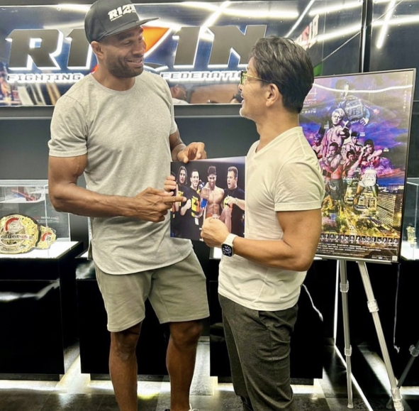 Alistair Overeem smiled while speaking with another man as the pair held a piece of combat sports memorabilia. The photograph offered a full-length view of his transformed physique. His gray T-shirt and shorts highlighted a tall but substantially leaner silhouette, with much of the bulk associated with his heavyweight career no longer apparent. The striking difference soon became a talking point among fight fans, some of whom remarked that they had never seen the decorated fighter looking so small. | Source: X/COMBAT SPORTS TODAY