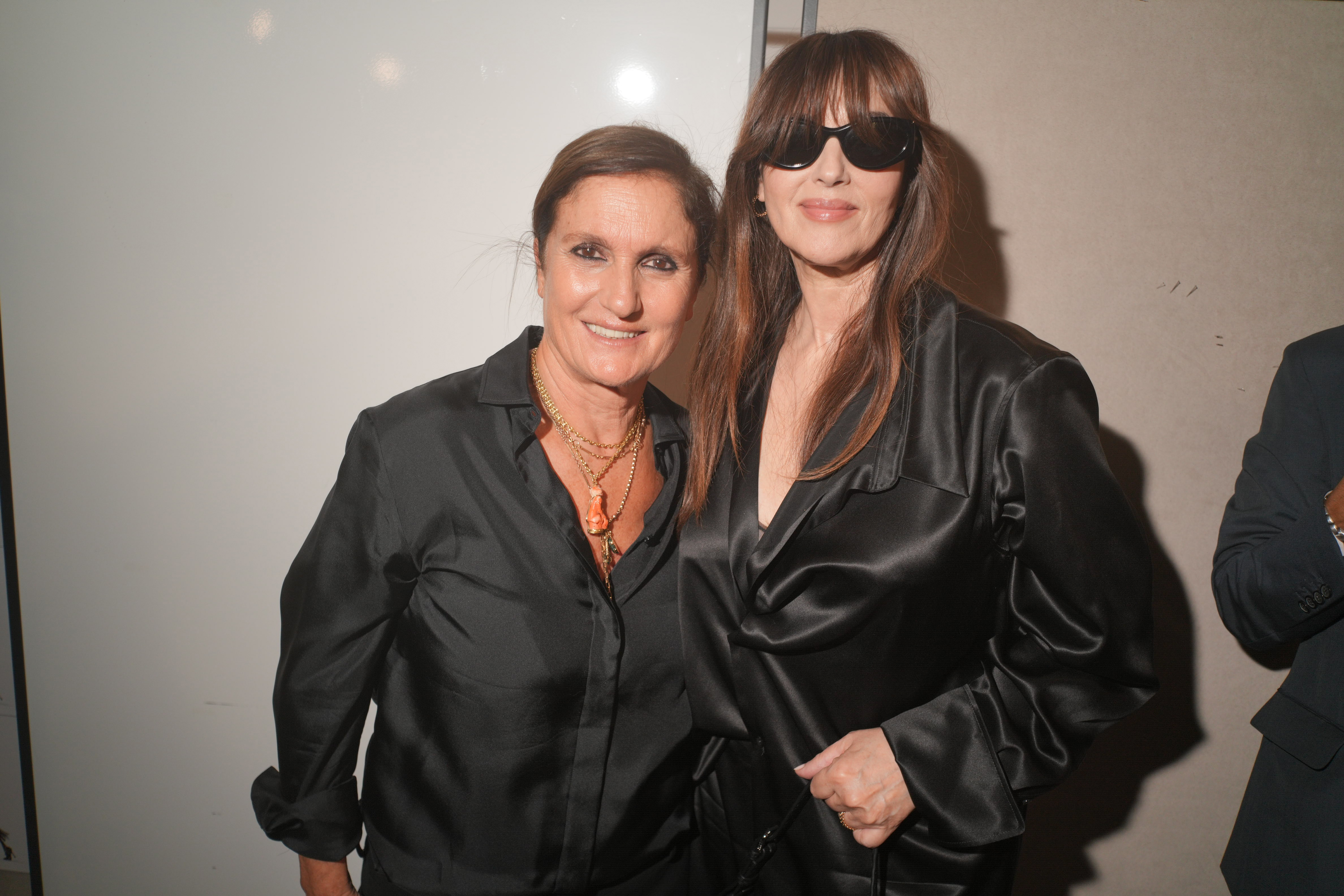 Fashion heavyweights crossed paths when Monica Bellucci caught up with designer Maria Grazia Chiuri inside the Fendi showcase that same day. Standing shoulder-to-shoulder, the duo shared a warm smile for the cameras, Chiuri styling layered gold chains over a classic dark button-up while Bellucci stood effortlessly chic in her glossy all-black getup. | Source: Getty Images