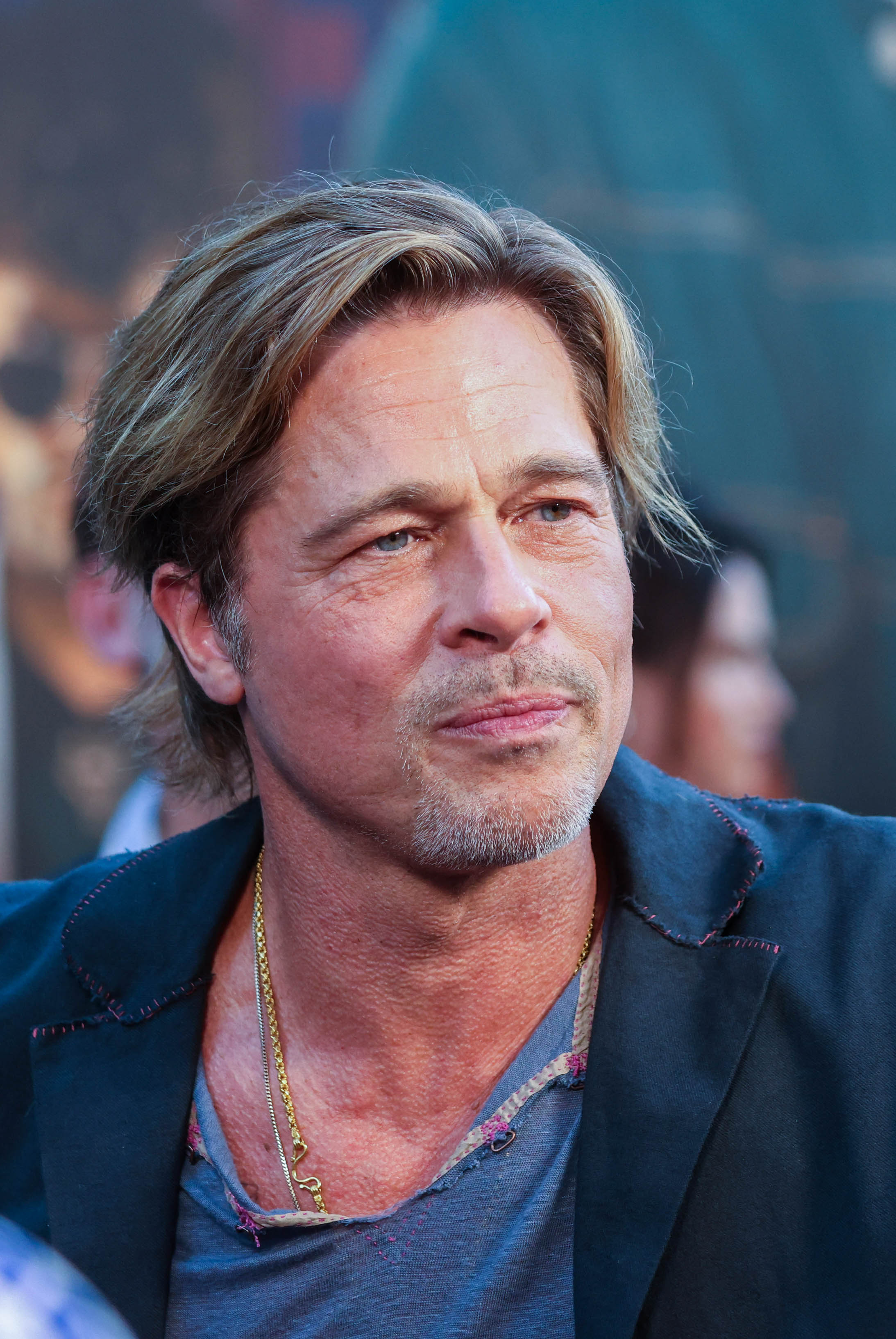 Brad Pitt appears with longer highlighted hair and light facial hair while attending the 2022 premiere of "Bullet Train" in Paris, wearing a relaxed dark outfit on the red carpet.