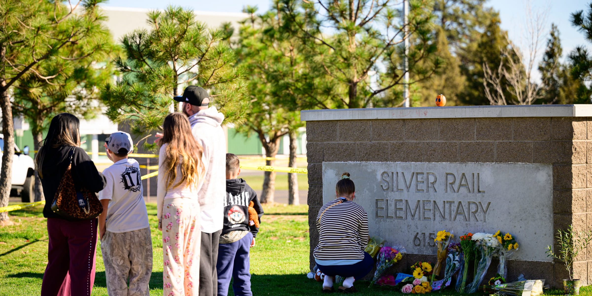 Community members grieve and lay flowers at the site of a makeshift memorial in front of Silver Rail Elementary School | Source: Getty Images
