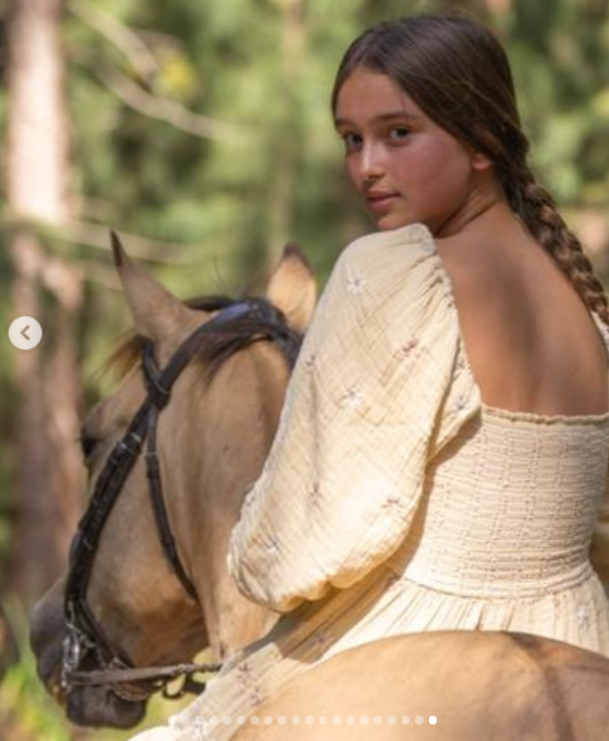 Arabella Kushner glanced over her shoulder while riding a horse through a sun-dappled forest, wearing a puff-sleeved butter-yellow dress with smocked detailing and her long brown hair styled in a neat braid. The outdoor snapshot showcased a quiet, scenic moment shared by Ivanka Trump in honor of her daughter's 15th birthday. | Source: Instagram/ivankatrump