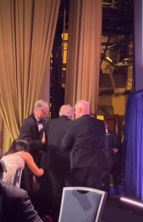 Security personnel and Secret Service agents tightly surround President Donald Trump near a curtained exit. | Source: Instagram/hellomag