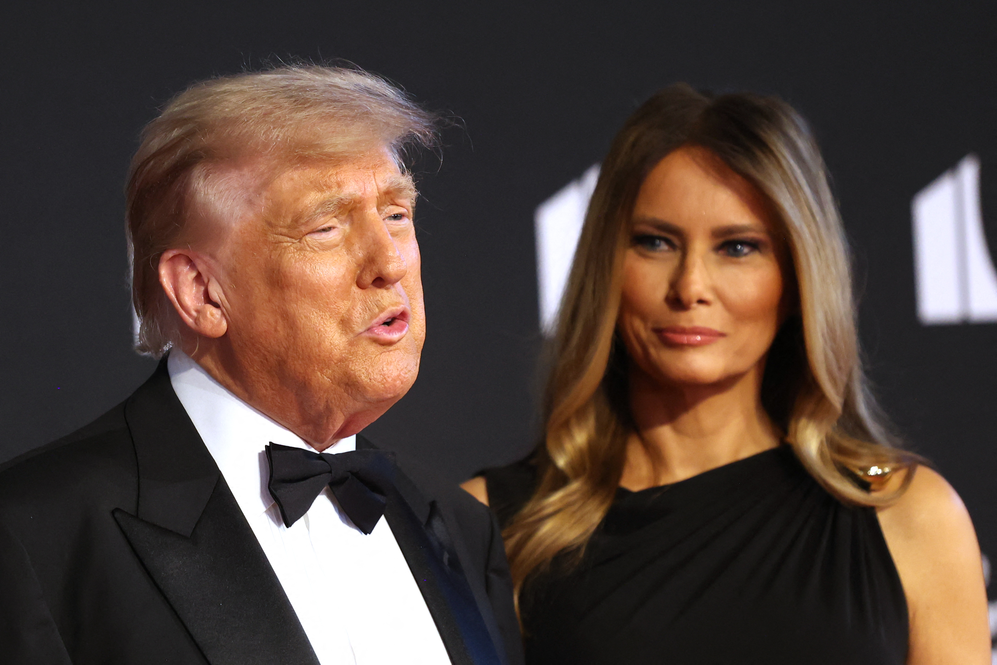 In a tight frame on the red carpet, the president appears to address the media while the first lady stands composed at his side, both set against the Kennedy Center's signature backdrop.