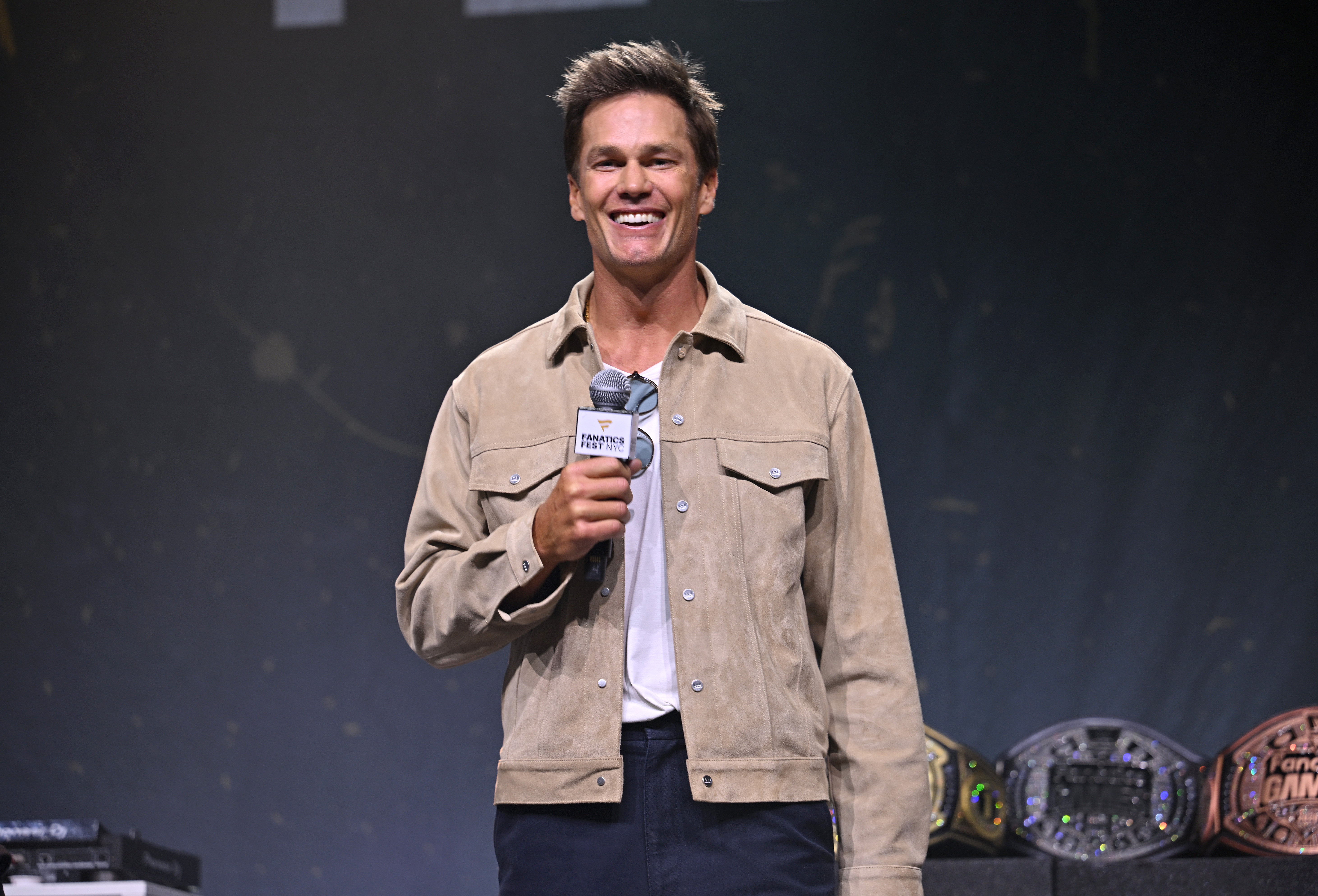 Tom Brady appeared onstage during Fanatics Fest NYC 2026 at the Jacob Javits Center in New York City on July 19. The public appearance offered another recent look at the retired quarterback, whose youthful facial features have continued to generate debate while prompting comparisons with photographs from earlier in his career.