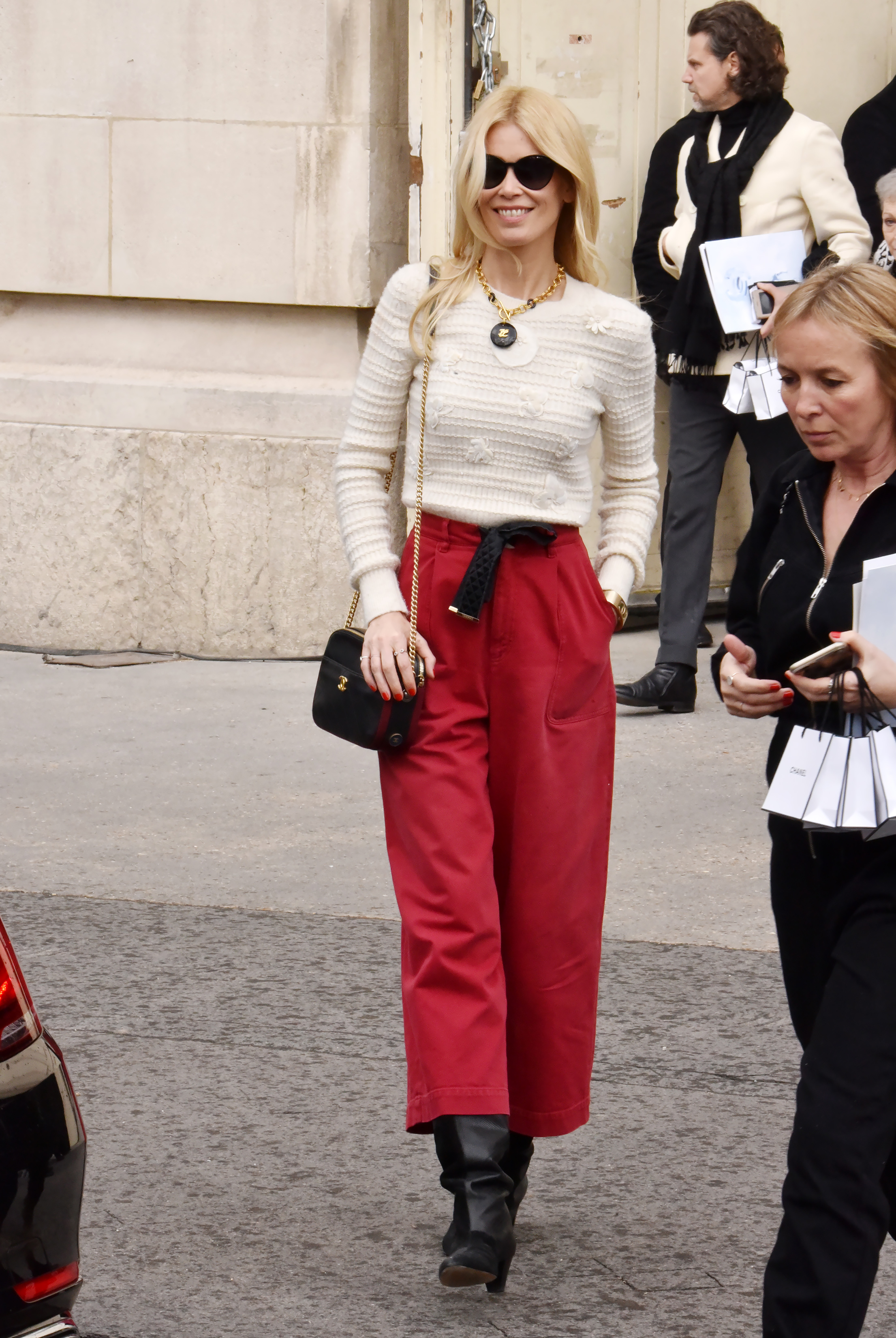 Claudia Schiffer steps out for the Chanel Fall/Winter show at Paris Fashion Week, effortlessly chic in bold red trousers and a textured ivory knit. With oversized sunglasses and a statement necklace, she channels modern elegance with a touch of Parisian flair.