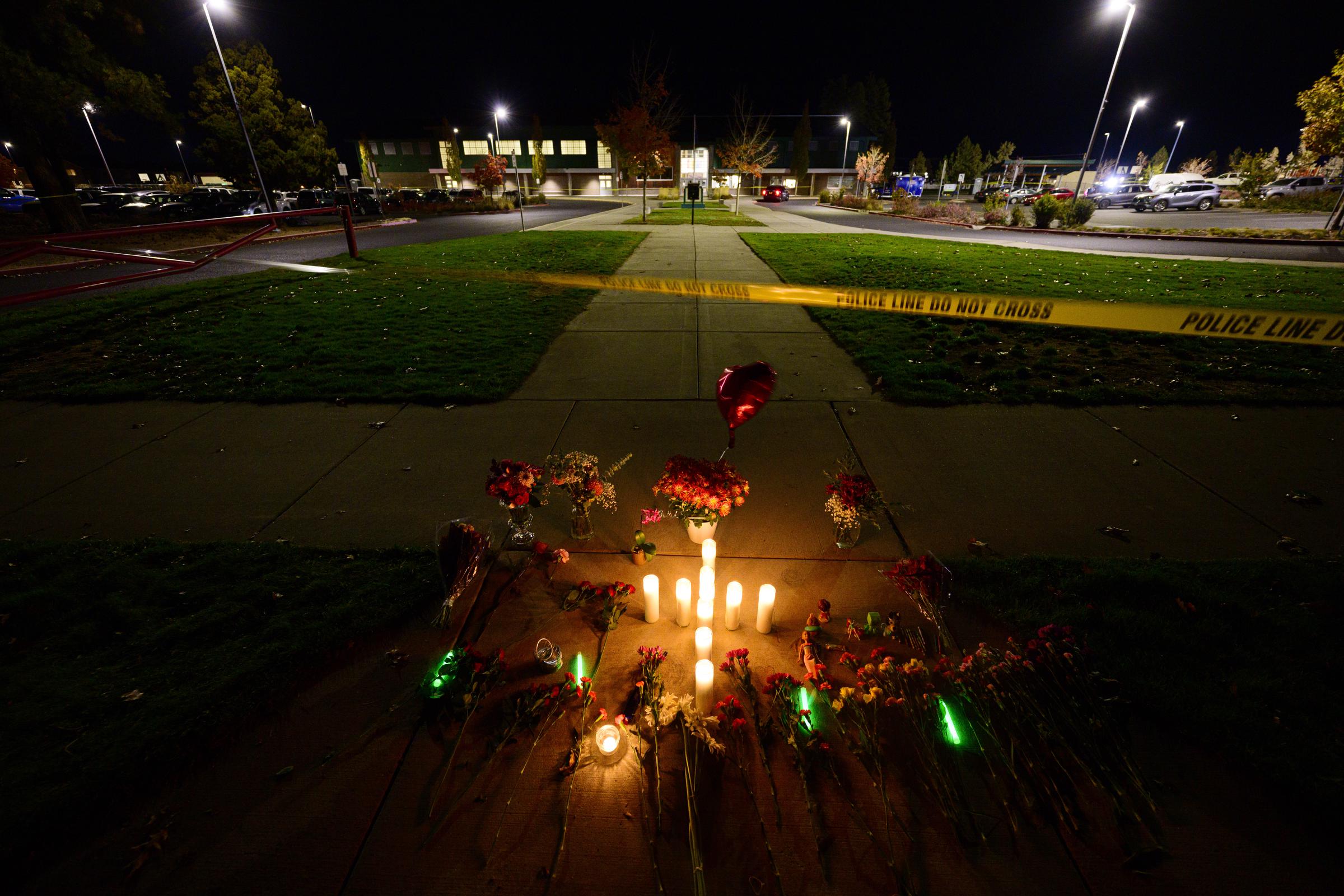 A candlelit memorial stands across from Silver Rail Elementary School while police tape blocks access to the grounds. | Source: Getty Images