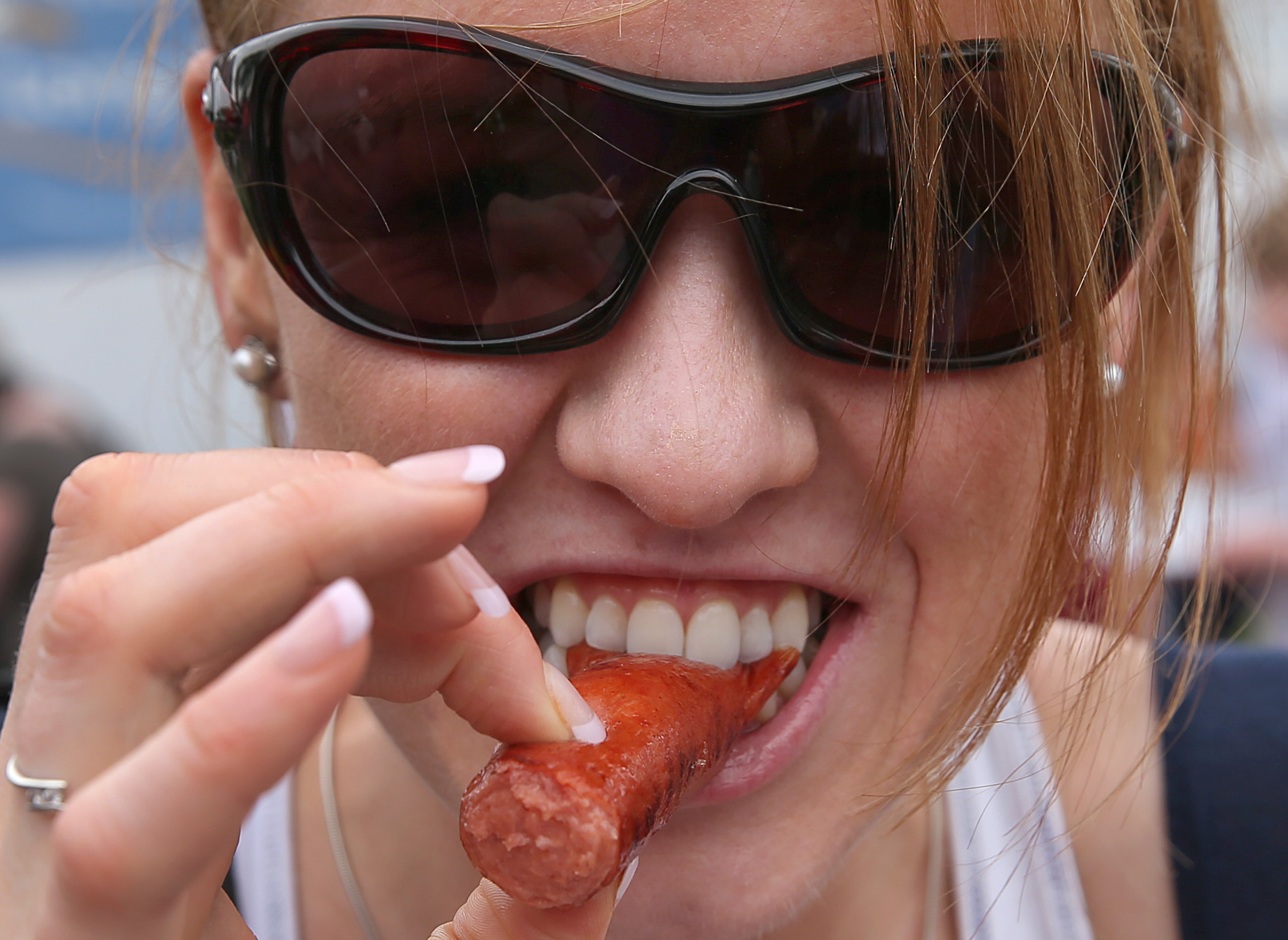 A woman bites into a grilled hot dog, one of the types of ready-to-eat meat products at the center of Kayem Foods' sweeping recall. | Source: Getty Images