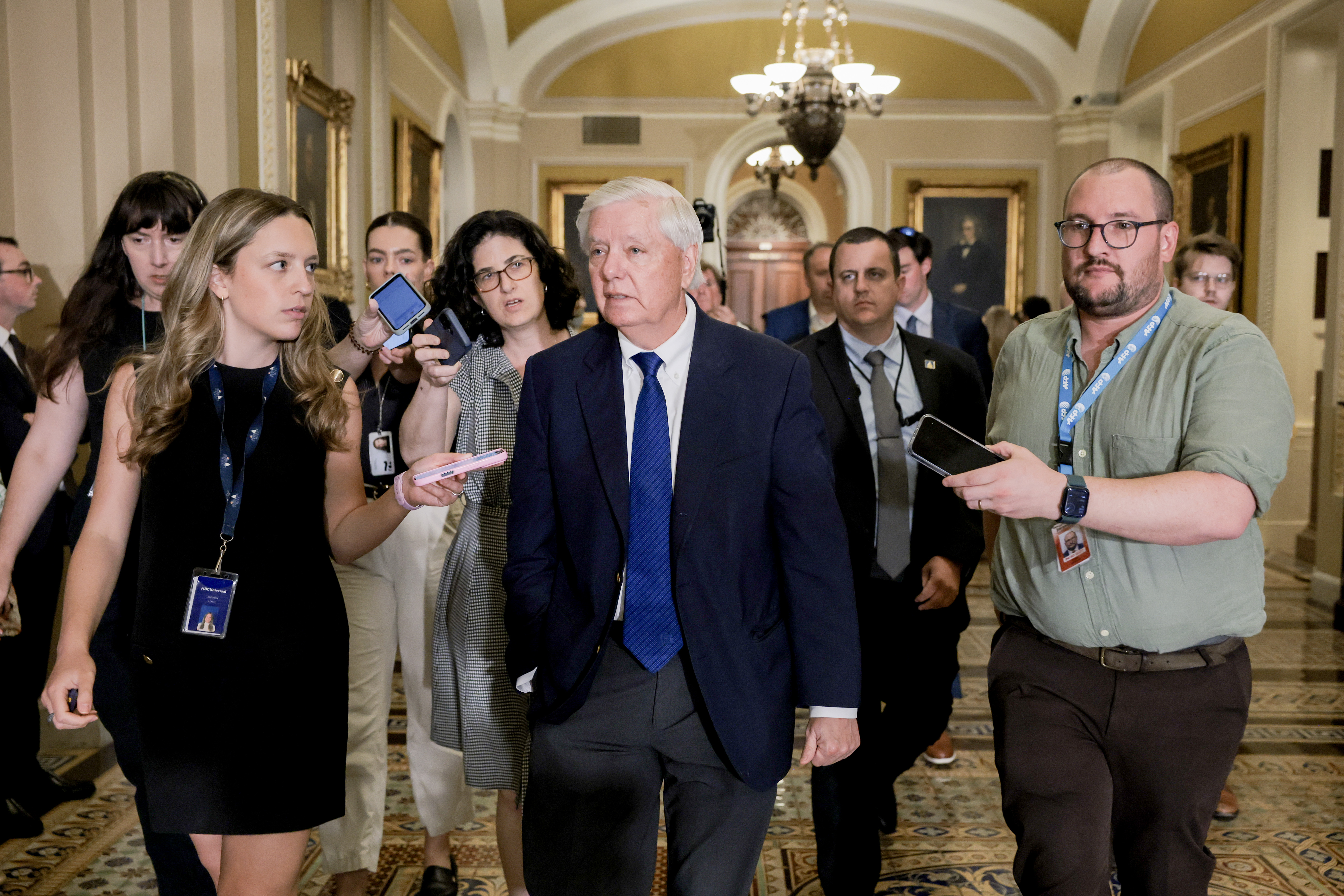 Lindsey Graham walks through the Capitol corridors surrounded by reporters, answering questions as he departs a Senate Republican policy luncheon following discussions on the day's legislative agenda. | Source: Getty Images