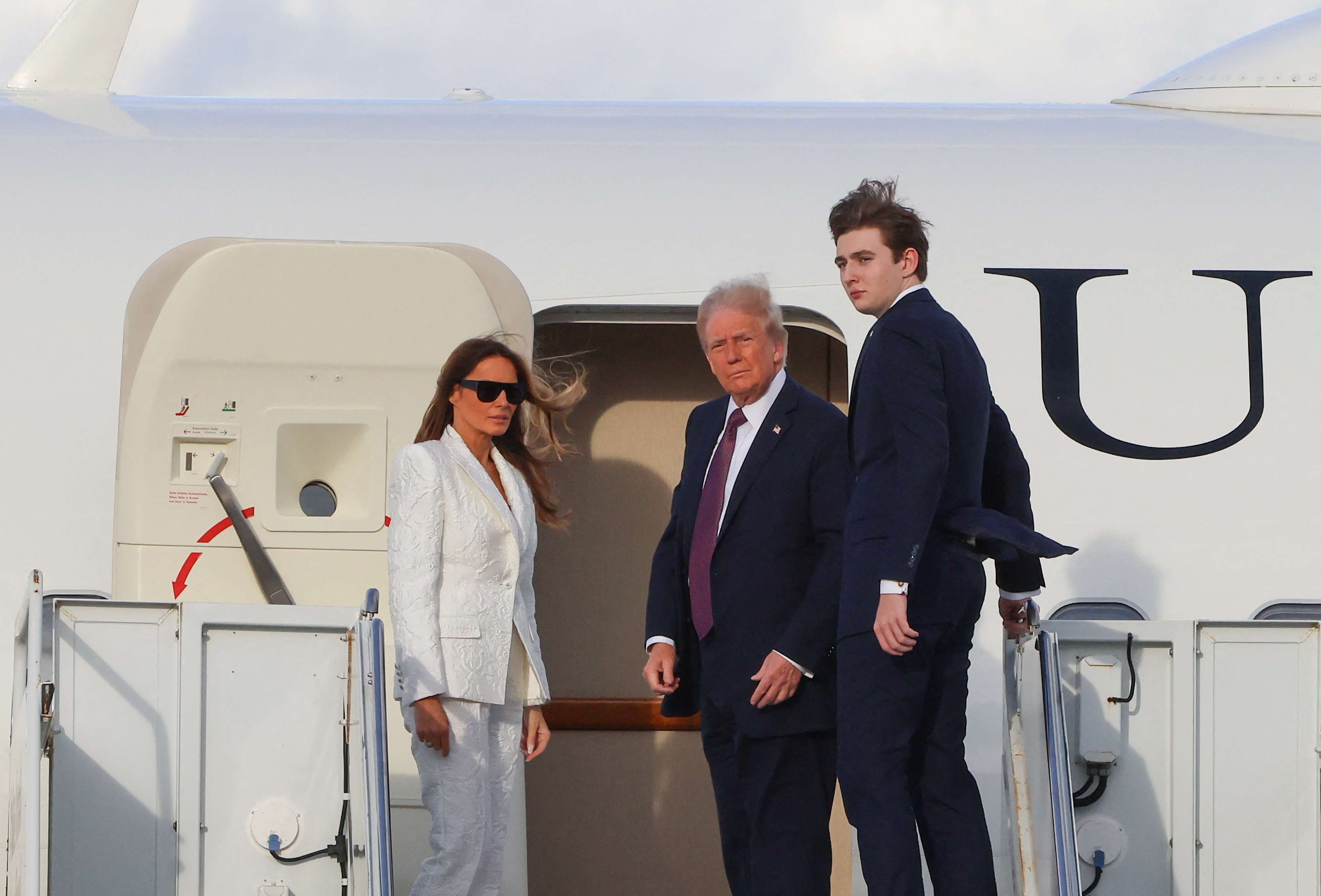 Donald, Melania, and Barron Trump board a US government aircraft at Palm Beach International Airport on January 18, 2025, in West Palm Beach, Florida | Source: Getty Images