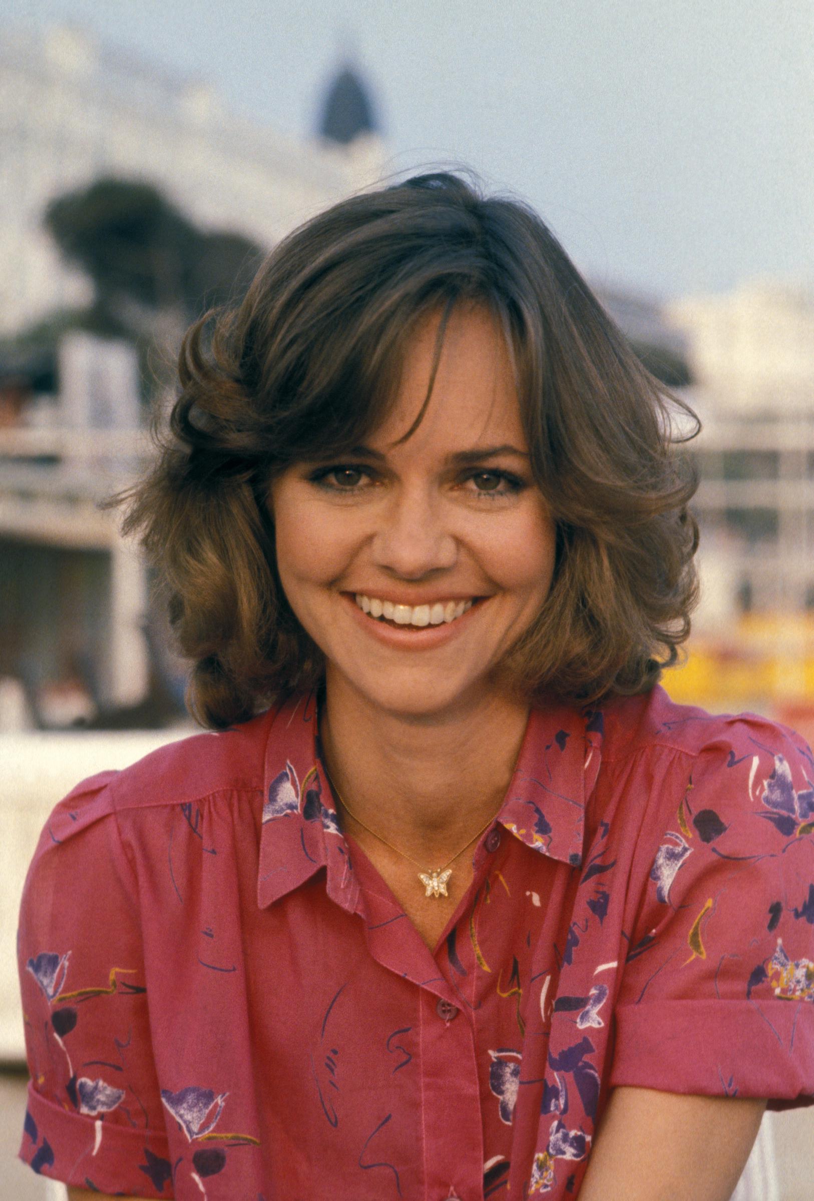 Sally Field at the Cannes Film Festival during the presentation of "Norma Rae." She beams with a wide smile that highlights her chubby cheeks, while her eyes reveal a playful charm.