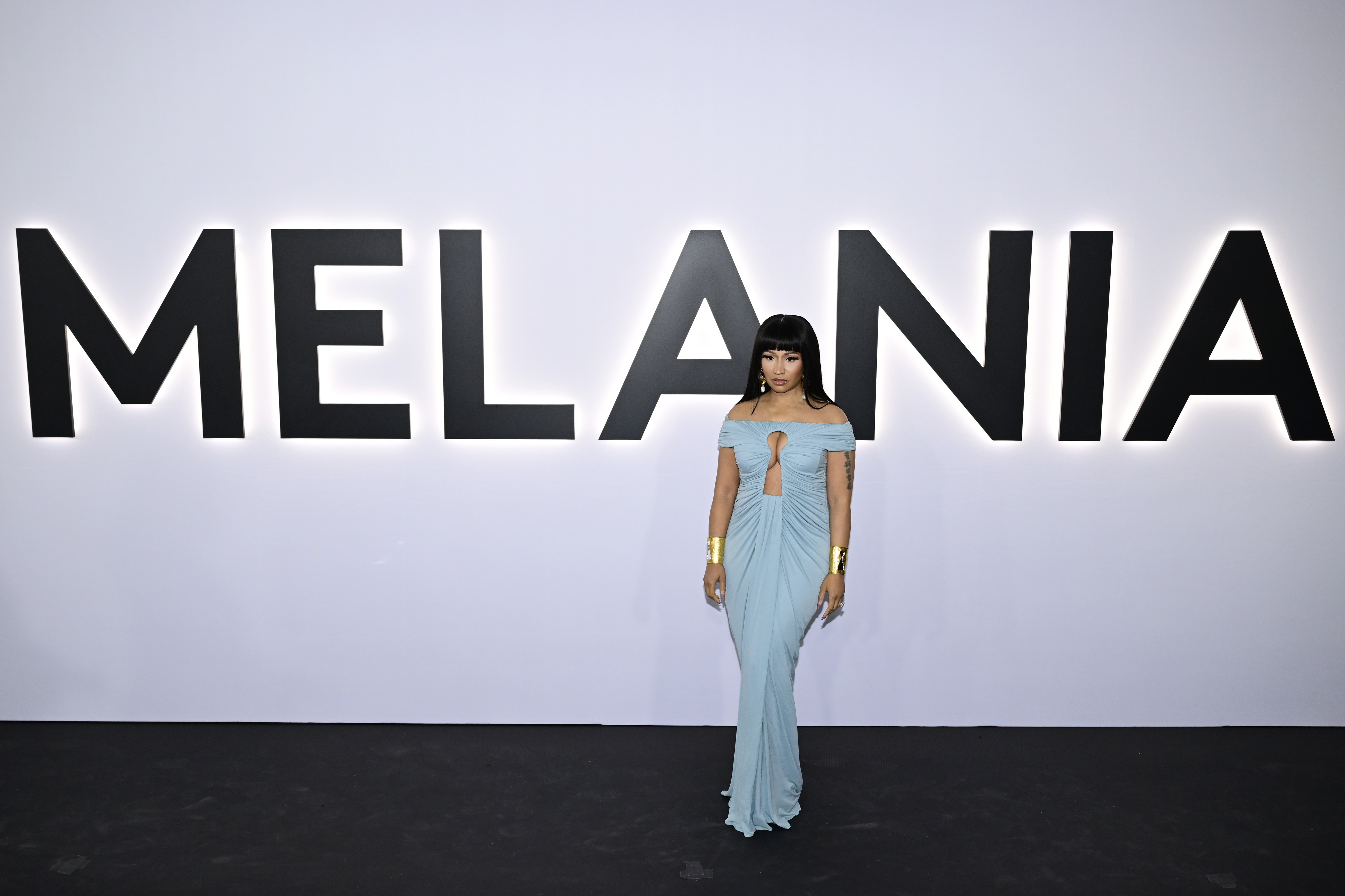 Nicki Minaj poses in front of the giant "MELANIA" sign at the documentary's premiere, wearing a pale-blue off-the-shoulder gown with gold cuffs — a striking reminder of her public connection to the first lady before the latest jokes about Donald Trump. | Source: Getty Images