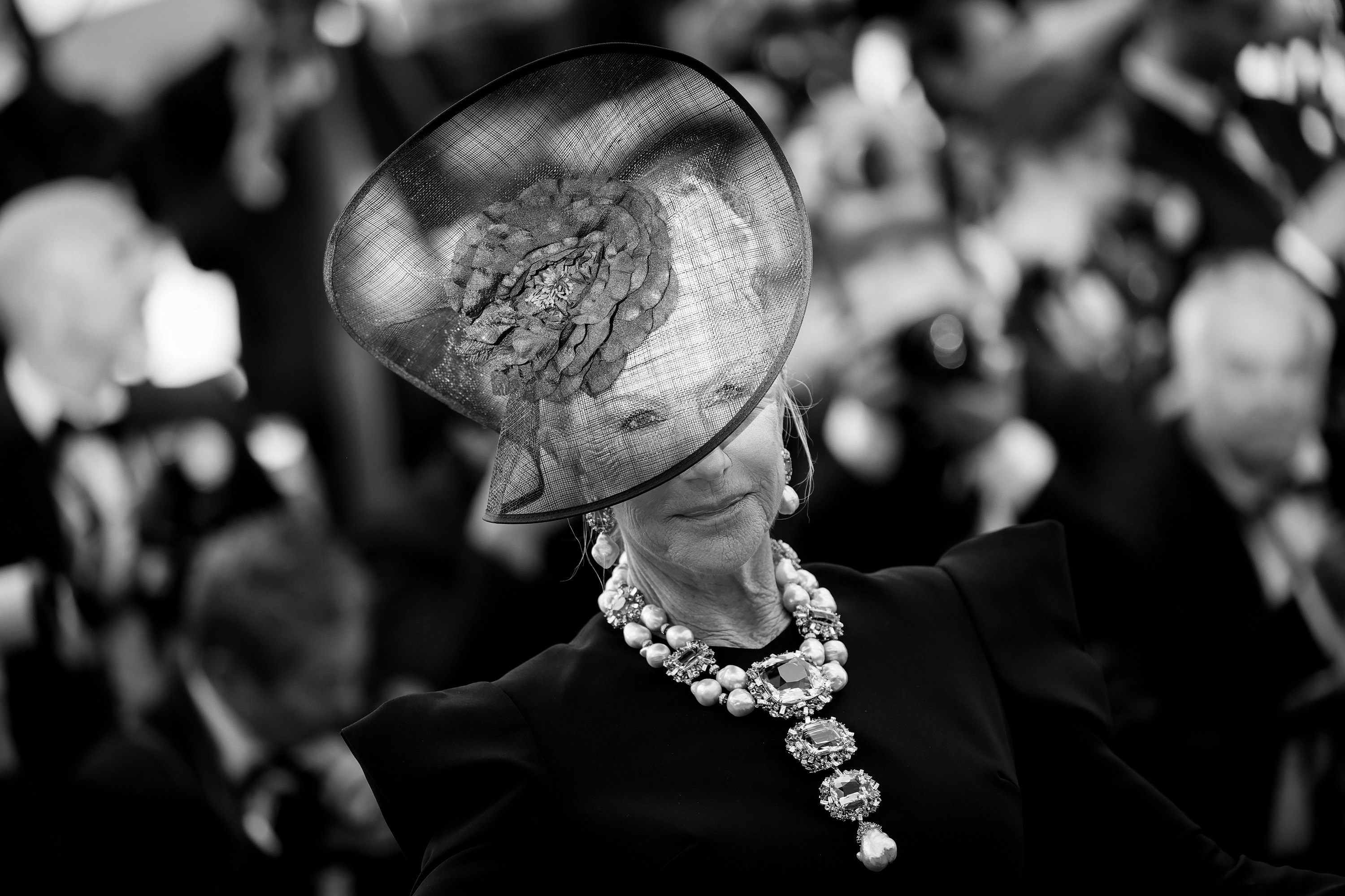 Helen Mirren attends the “La Venue De L’avenir” (Colours of Time) red carpet at the 78th annual Cannes Film Festival at the Palais des Festivals on May 22, 2025. She wears a structured black ensemble paired with a sweeping floral fascinator and a show-stopping gem-and-pearl necklace.