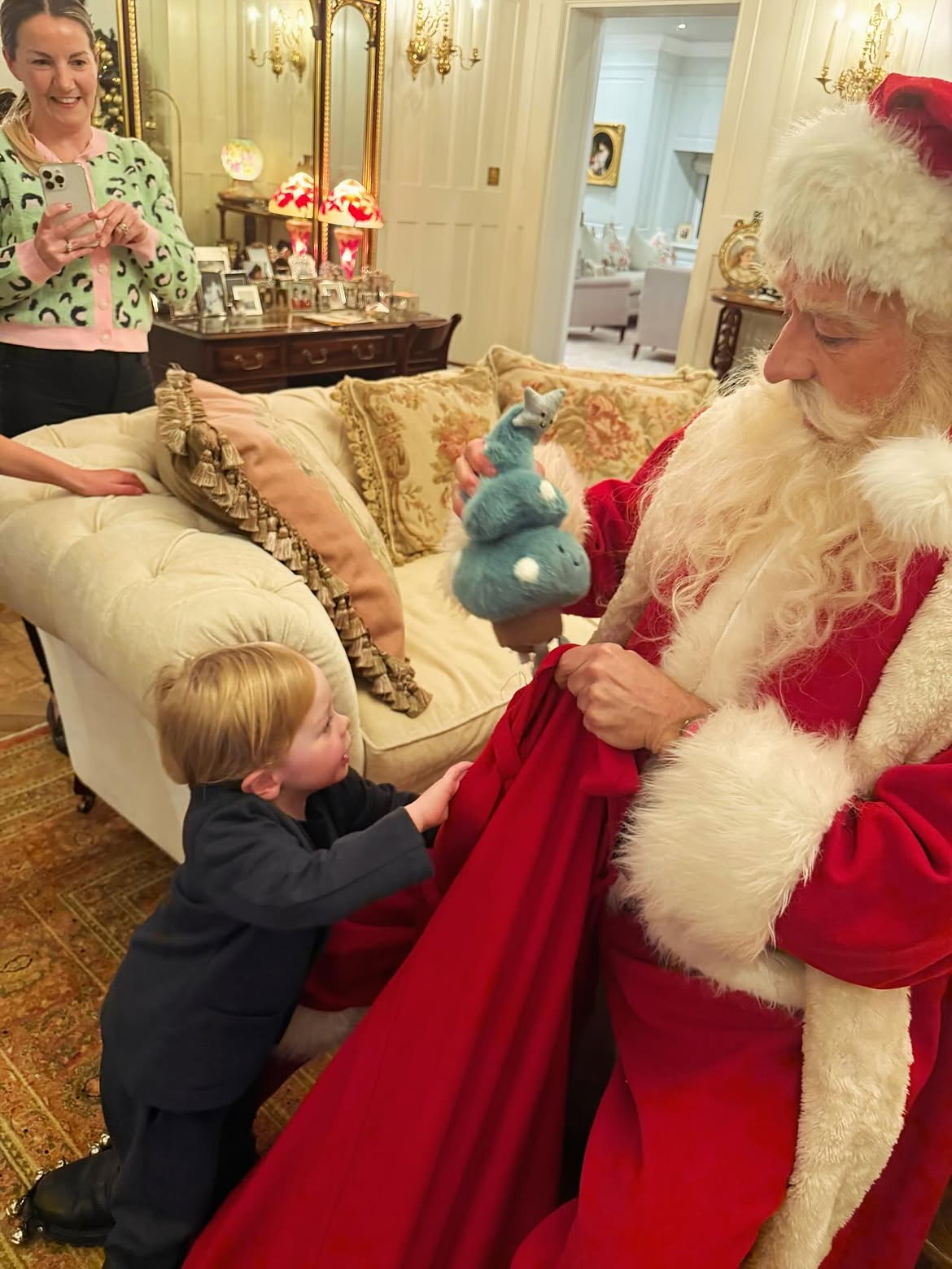 Little Sidney enjoyed a personal visit from Santa, who entertained him with a blue stuffed dinosaur while a family member captured the sweet moment on her phone. | Source: Instagram/@kellyosbourne