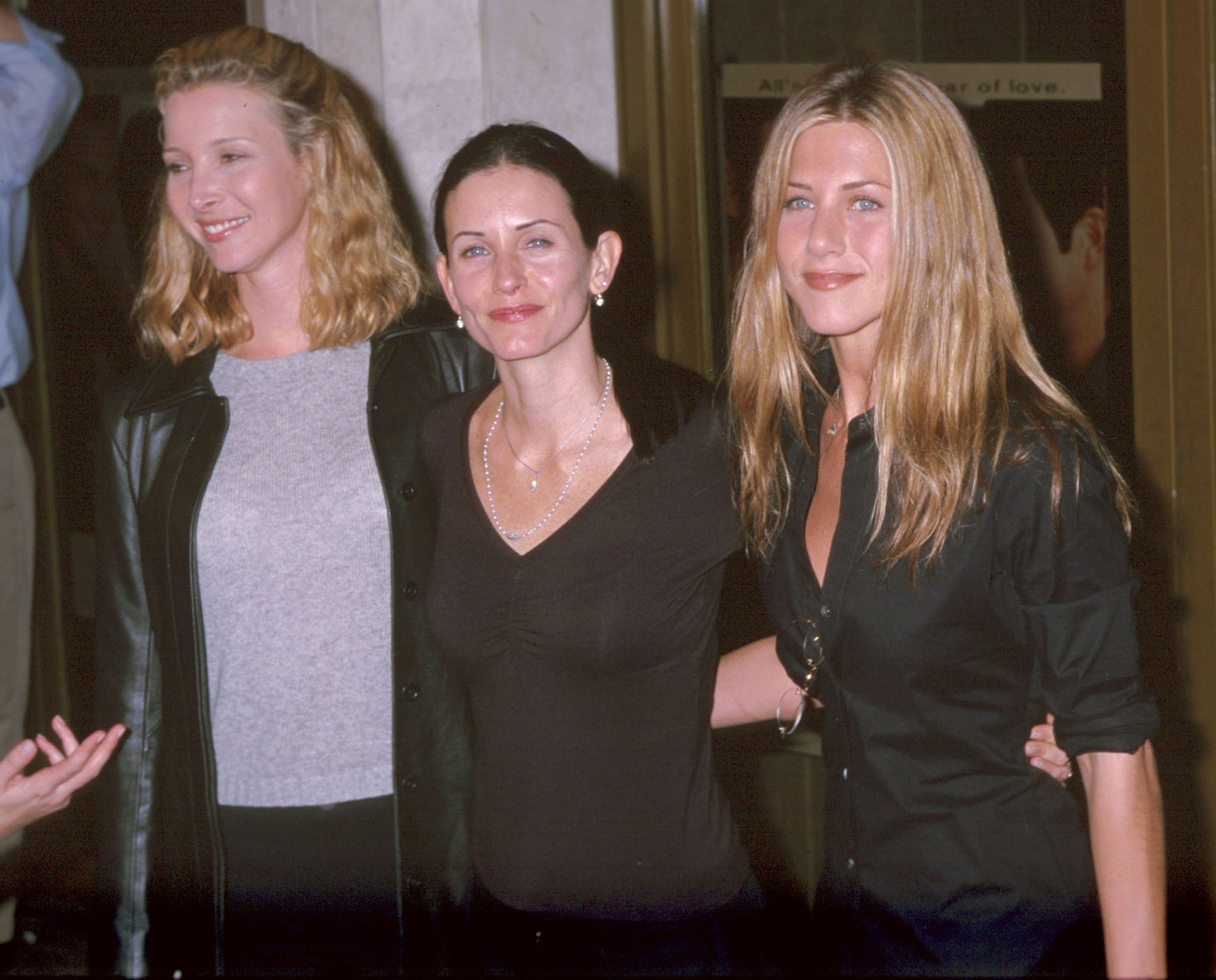 Joined by Lisa Kudrow, Courteney Cox and Jennifer Aniston attend the Los Angeles premiere of "Three to Tango." Kudrow, with her blonde hair, stands on one side while Cox, with her dark hair styled in a bun, is positioned between her and Aniston.