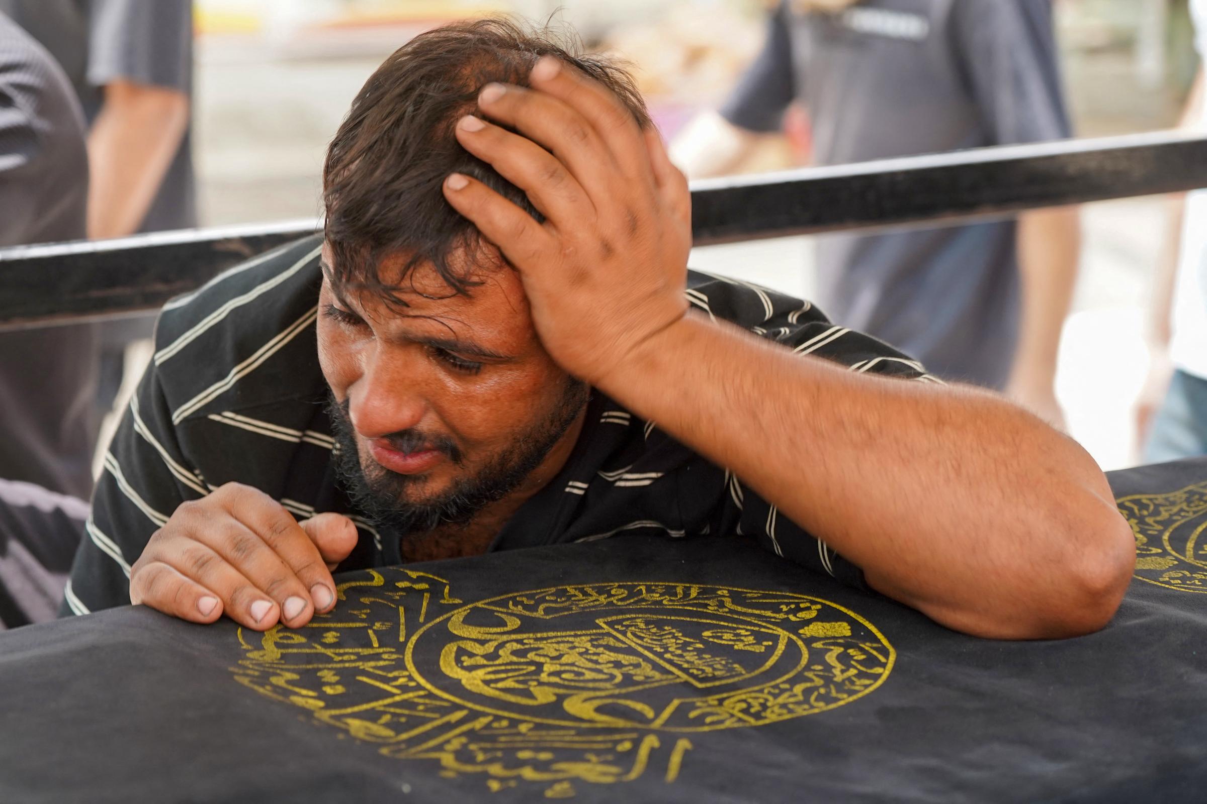 A man weeps over the coffin of a relative killed in the Hyper Mall fire in Kut, Iraq on July 17, 2025. | Source: Getty Images