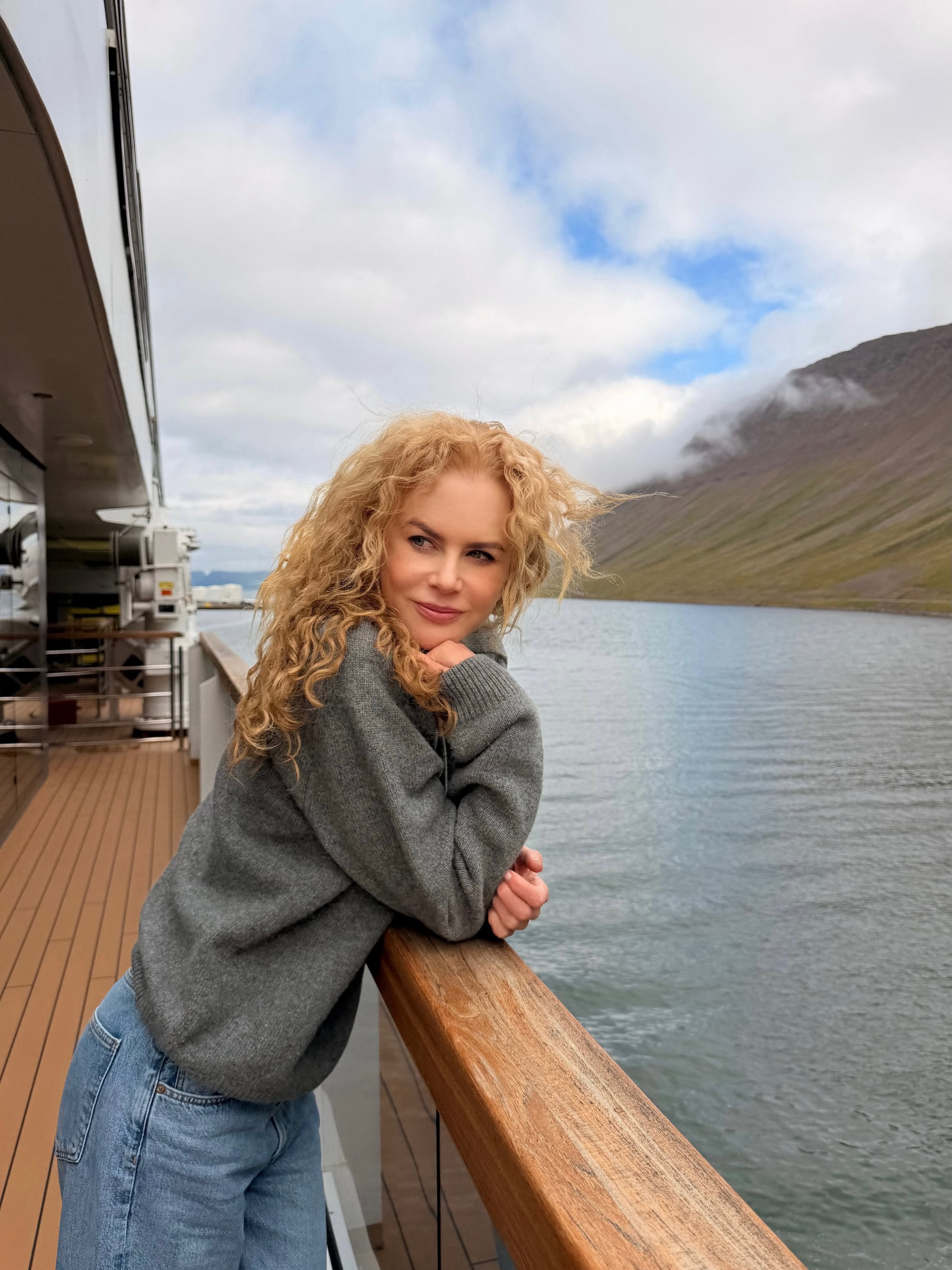 Nicole Kidman shows off her signature natural curls while leaning against the railing of a luxury Ritz-Carlton yacht off the coast of Iceland. Wearing a cozy gray sweater and denim jeans, the star embraced the windswept look during her family getaway. | Source: Instagram/nicolekidman