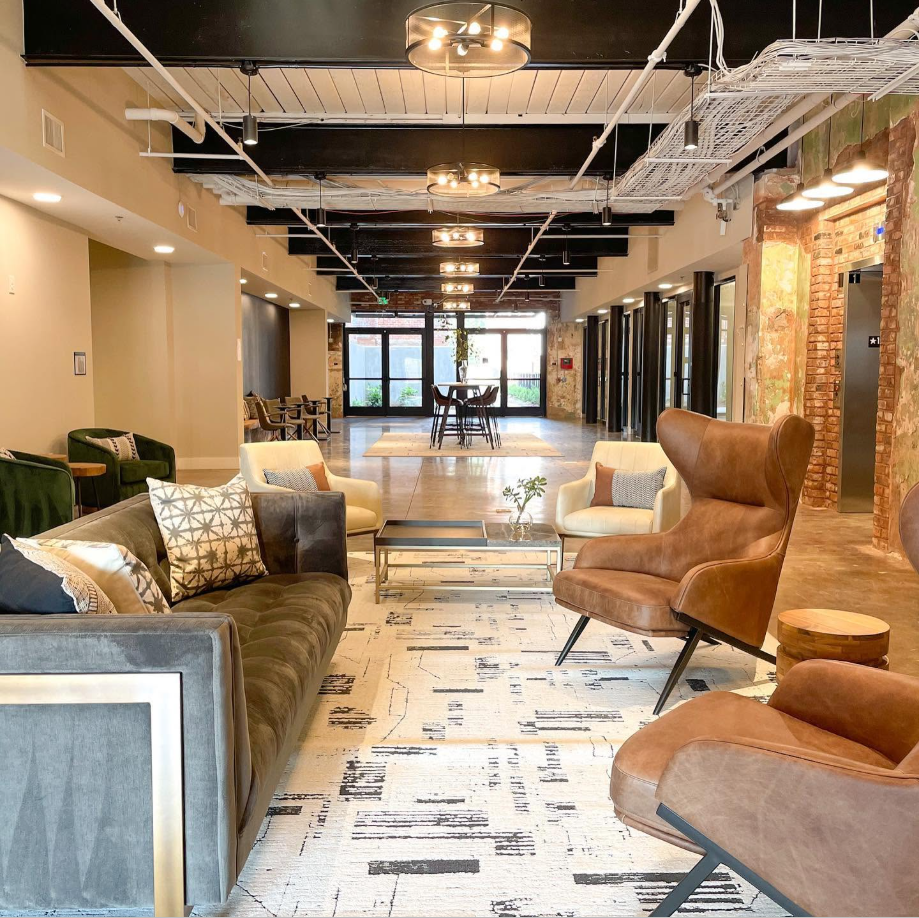The shared lounge extends toward the entrance, where casual seating and communal tables give the former mill space a more social, lived-in feel. | Source: Facebook/Judson Mills Loft