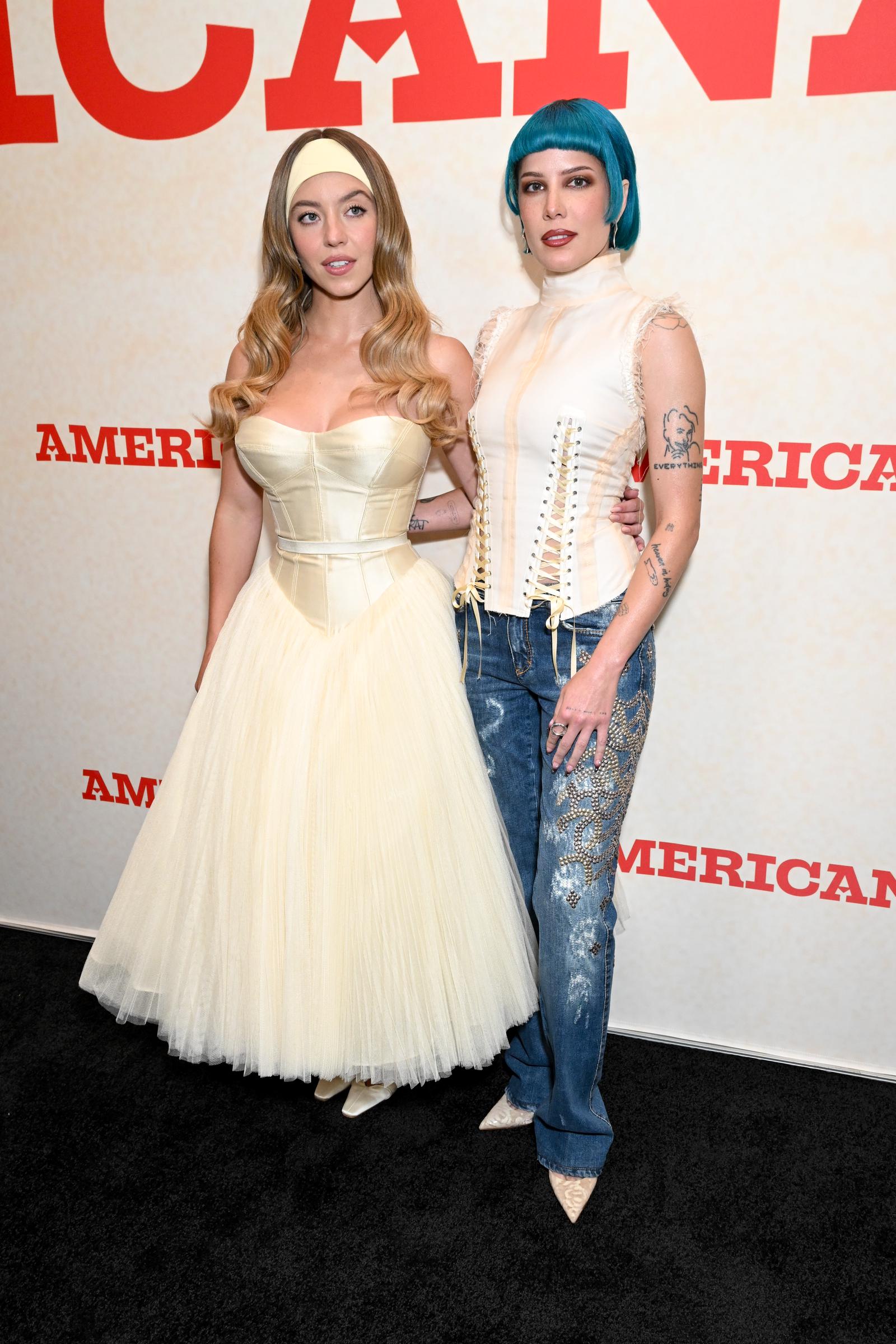 In this full-length shot, Sydney Sweeney poses alongside Halsey, the two sharing a light moment on the red carpet. Sweeney’s voluminous ivory gown contrasts with Halsey’s edgier look, while her headband adds a soft, playful accent to the elegant ensemble.