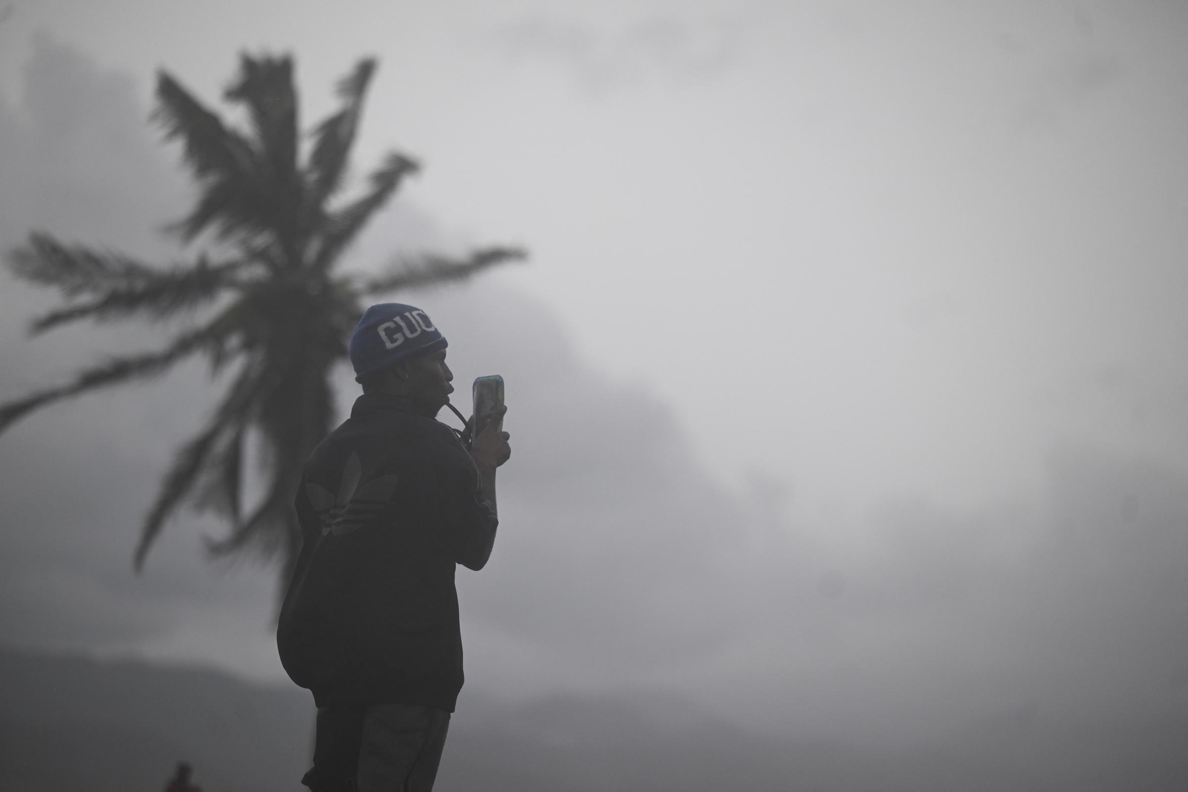 For illustration purposes: Brave onlookers and residents face the elements to document the dark, heavily overcast skies and gusty winds as a major storm moves ashore. | Source: Getty Image