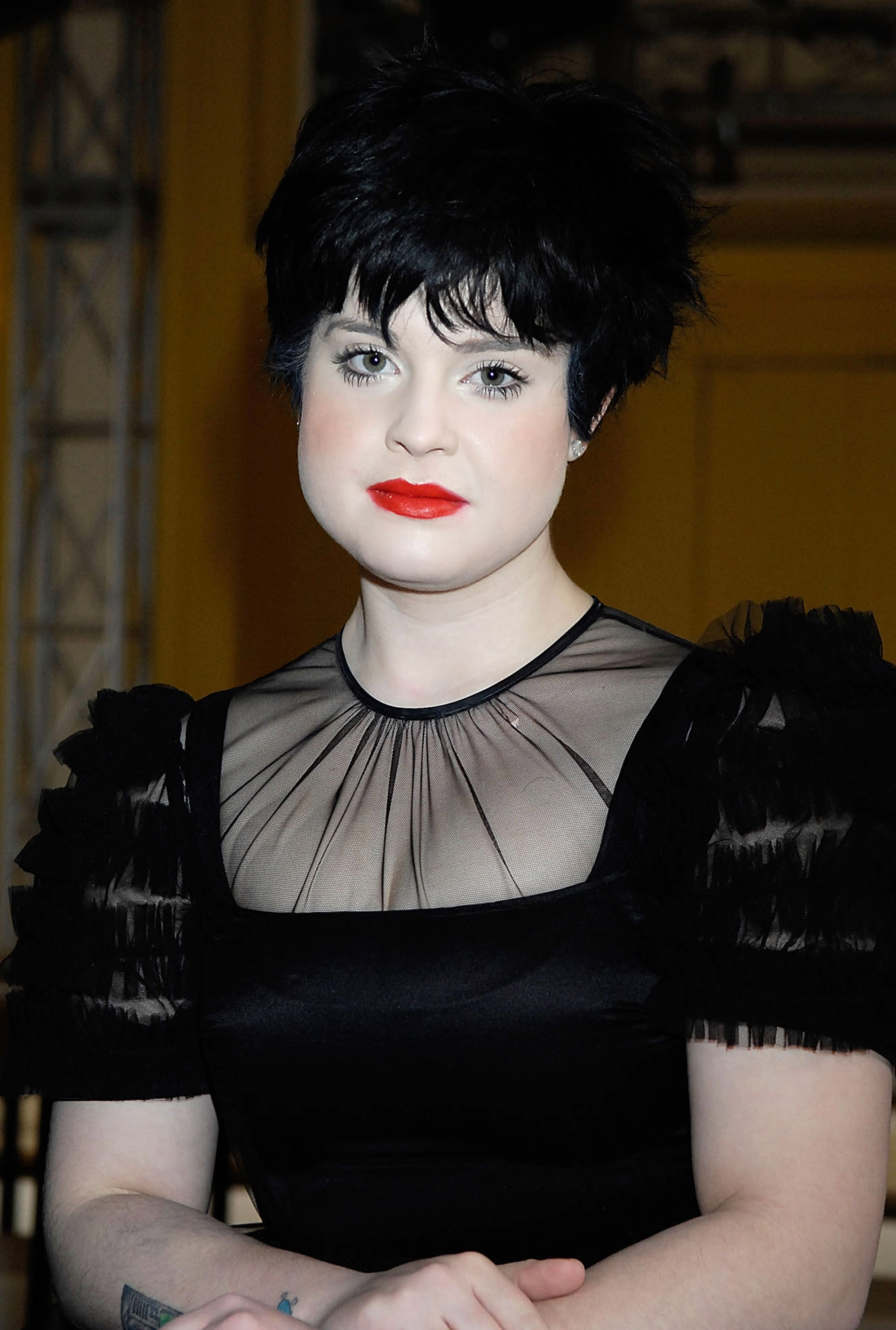 Kelly Osbourne arrives at the Luella show during London Fashion Week in 2008, embracing high-fashion elegance with a dramatic cropped hairstyle, bold red lipstick, and a refined look that marked a departure from her earlier punk-inspired image. | Source: Getty Images