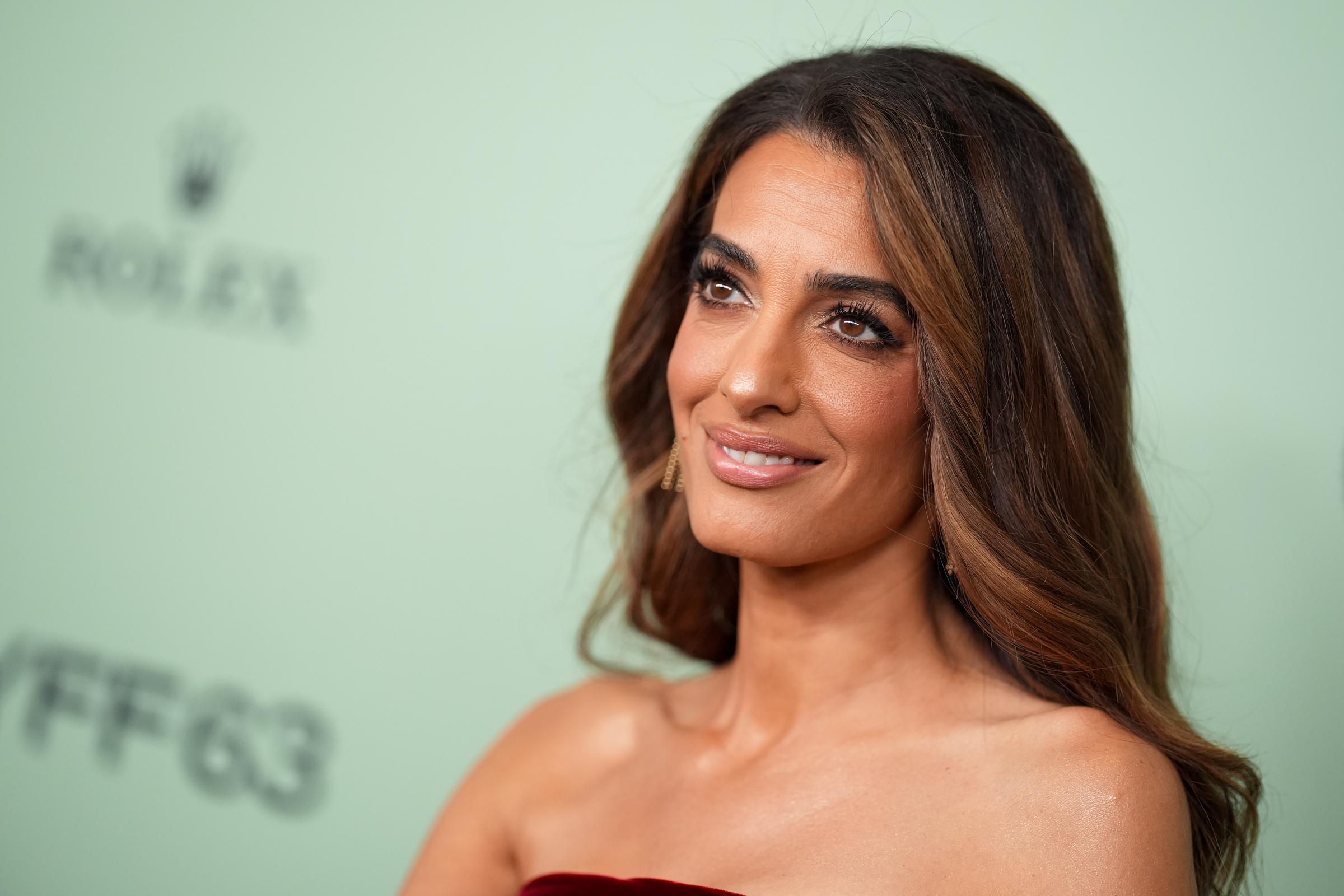 With her signature poise, Amal Clooney turns slightly toward the cameras, letting the intricate ruching and rich velvet of her strapless gown speak for itself.