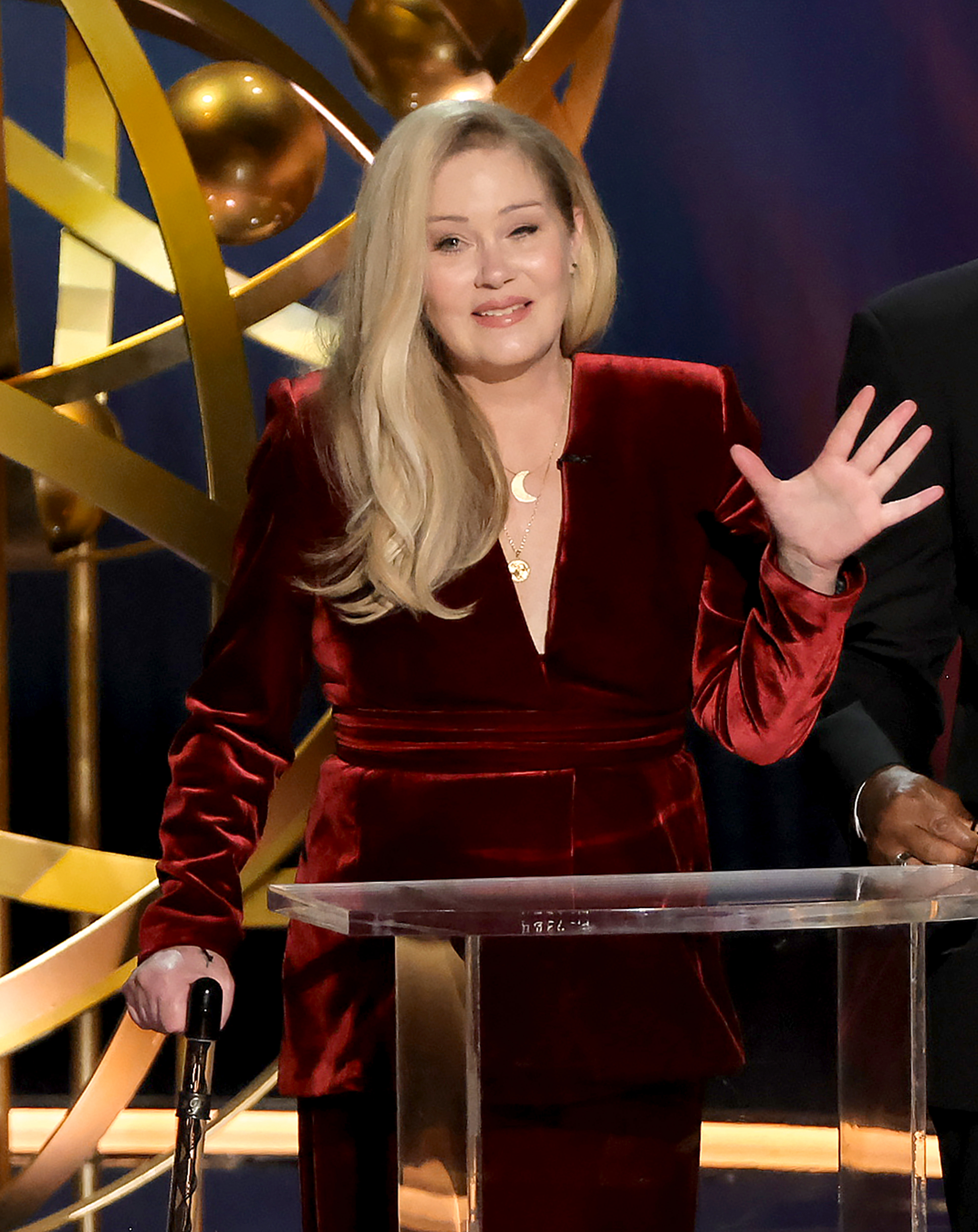 Christina Applegate greeted the audience from the podium during the 75th Primetime Emmy Awards at the Peacock Theater on January 15, 2024, in Los Angeles, California. Looking radiant as she acknowledged a standing ovation, the actress stood with the support of a decorative cane and waved onstage in a rich burgundy velvet suit featuring a deep V-neckline, complemented by layered necklaces and soft, side-swept waves. | Source: Getty Images