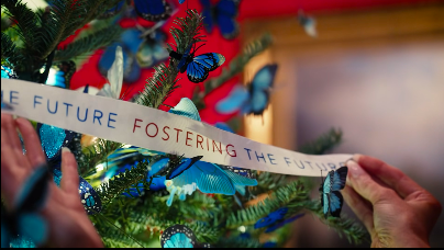 Melania Trump using her hands to place a banner on top of the butterfly-filled Christmas tree. | Source: Facebook/First Lady Melania Trump