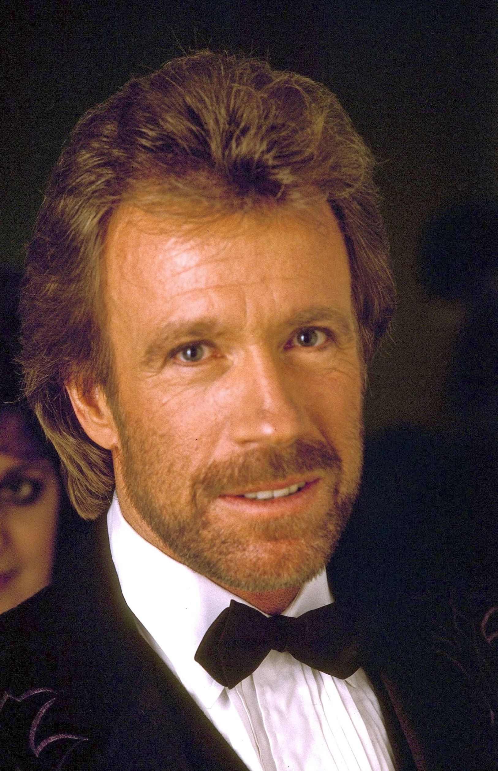 Chuck Norris attends a public event during the 1980s, by which point he had become one of Hollywood's biggest action stars. While audiences knew him for his martial arts skills and blockbuster films, Chuck remained unaware that his eldest daughter, Dianna "Dina" DeCioli, had been growing up believing another man was her father until she learned the truth as a teenager.