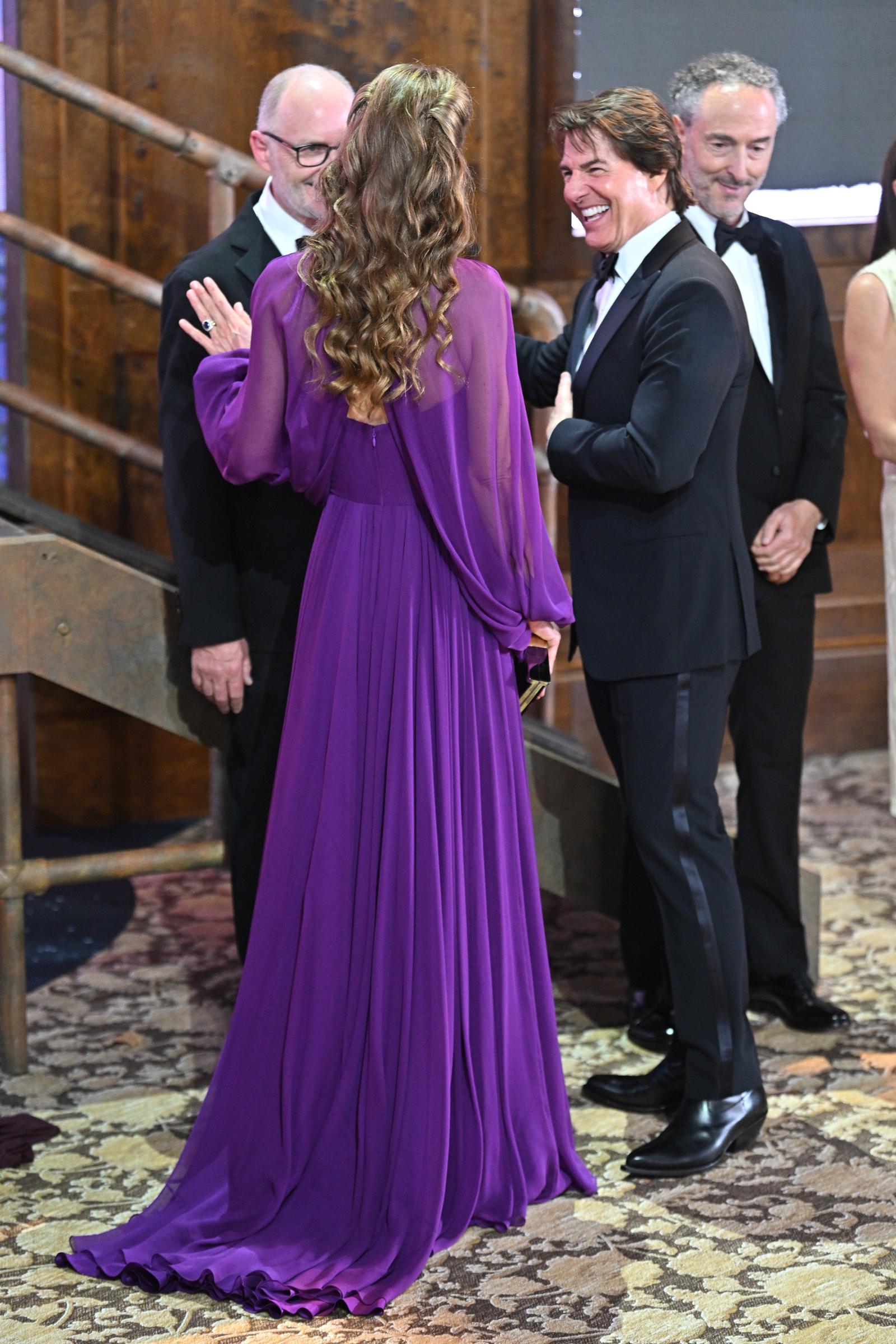 Catherine and Tom are pictured together inside Leicester Square Gardens during the "Digger" Film and TV Charity Royal Film Performance and Global Premiere. The rear view shows the draped back and floor-length train of Catherine's gown.