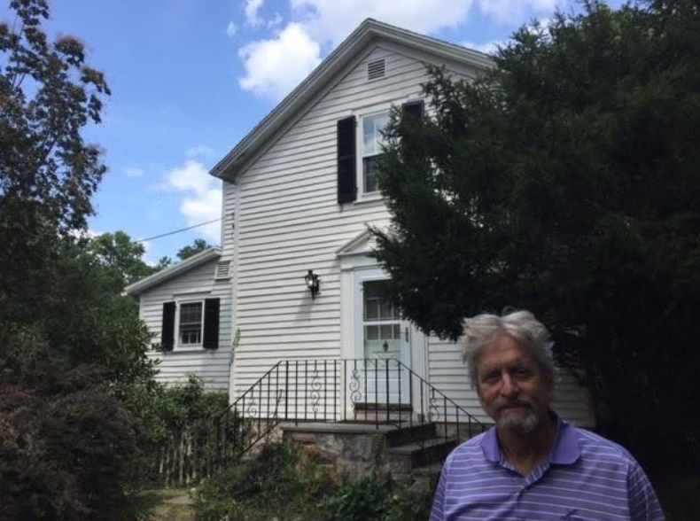 Michael stands outside the white clapboard house in Westport, Connecticut, where he said he lived from 1956 to 1963. The modest exterior offers a striking contrast to the sprawling estates he would own later in life. | Source: Facebook/MichaelDouglasOfficial