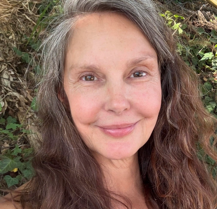 Judd smiles for a close-up selfie in 2026, with silver strands visible throughout her long brown hair. The photo offers a clear view of her natural-looking hair color without an elaborate hairstyle. | Source: Facebook/AshleyJuddOfficial