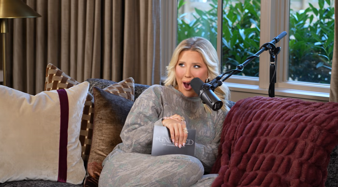 Savannah Chrisley reacts playfully into her microphone while recording an episode of her podcast, "Unlocked with Savannah Chrisley," on October 27, 2026, lounging comfortably on a sofa in a relaxed patterned gray loungewear set. | Source: YouTube/Savannah Chrisley