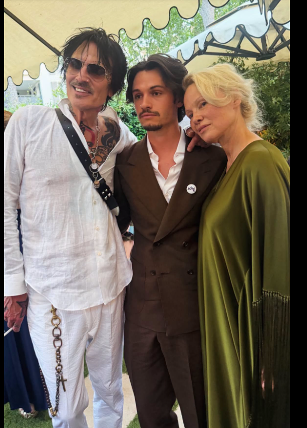 Dylan Lee stood between his parents, Tommy Lee and Pamela Anderson, as both leaned affectionately toward him in the family photo. Pamela’s flowing olive-green fringed dress was seen clearly beside Tommy’s relaxed all-white look. | Source: Facebook/Realiteatv