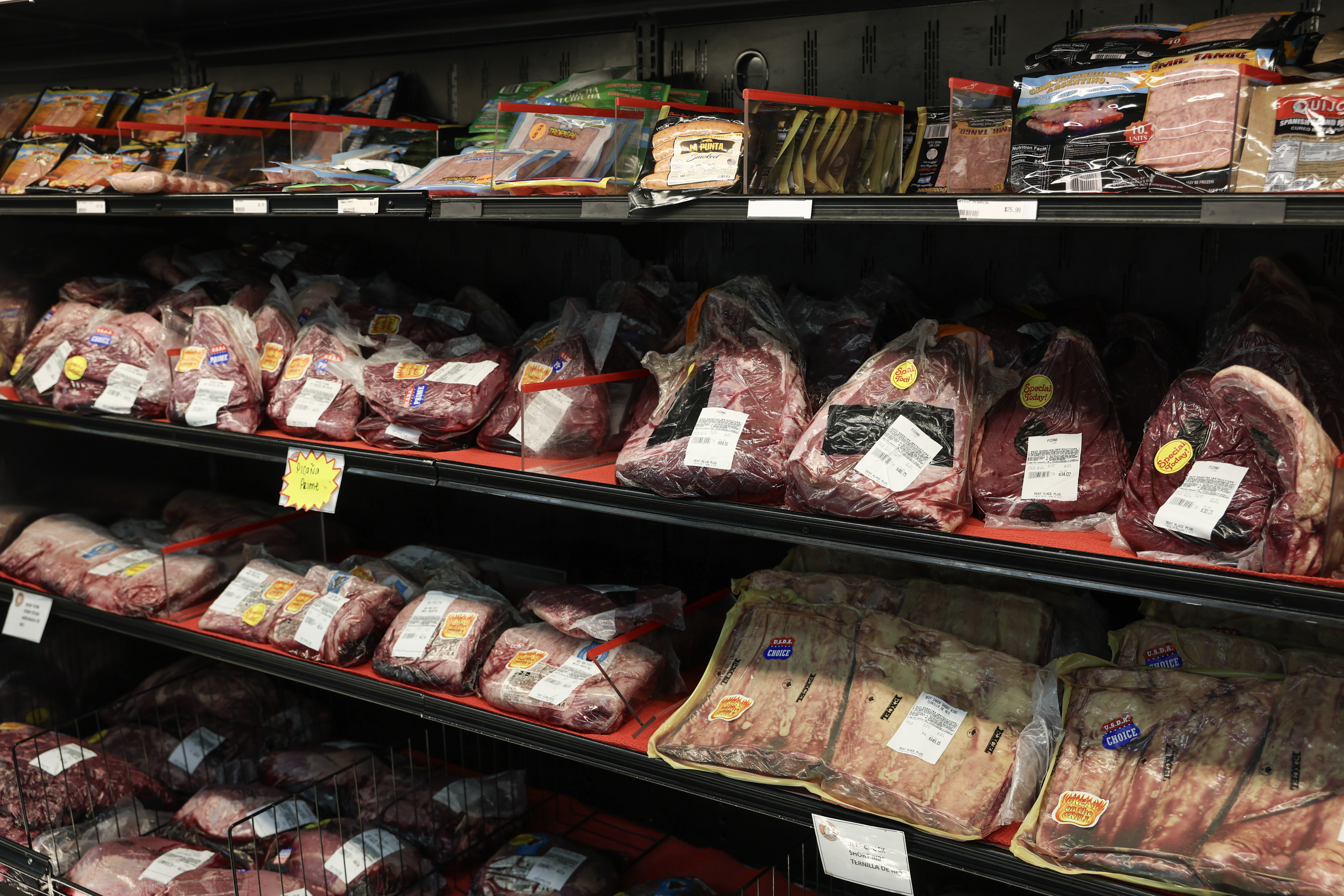 Assorted fresh and packaged meats fill a refrigerated display case at a grocery store. | Source: Getty Images
