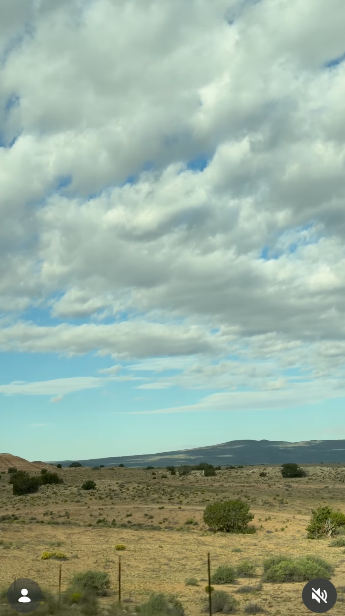 A wide desert vista captured beneath sweeping cumulus clouds and pale blue skies during a Southwestern trip on October 11, 2026. Low arid brush, scattered greenery, and gentle mountain silhouettes define the serene, open terrain. | Source: Instagram/selmablair