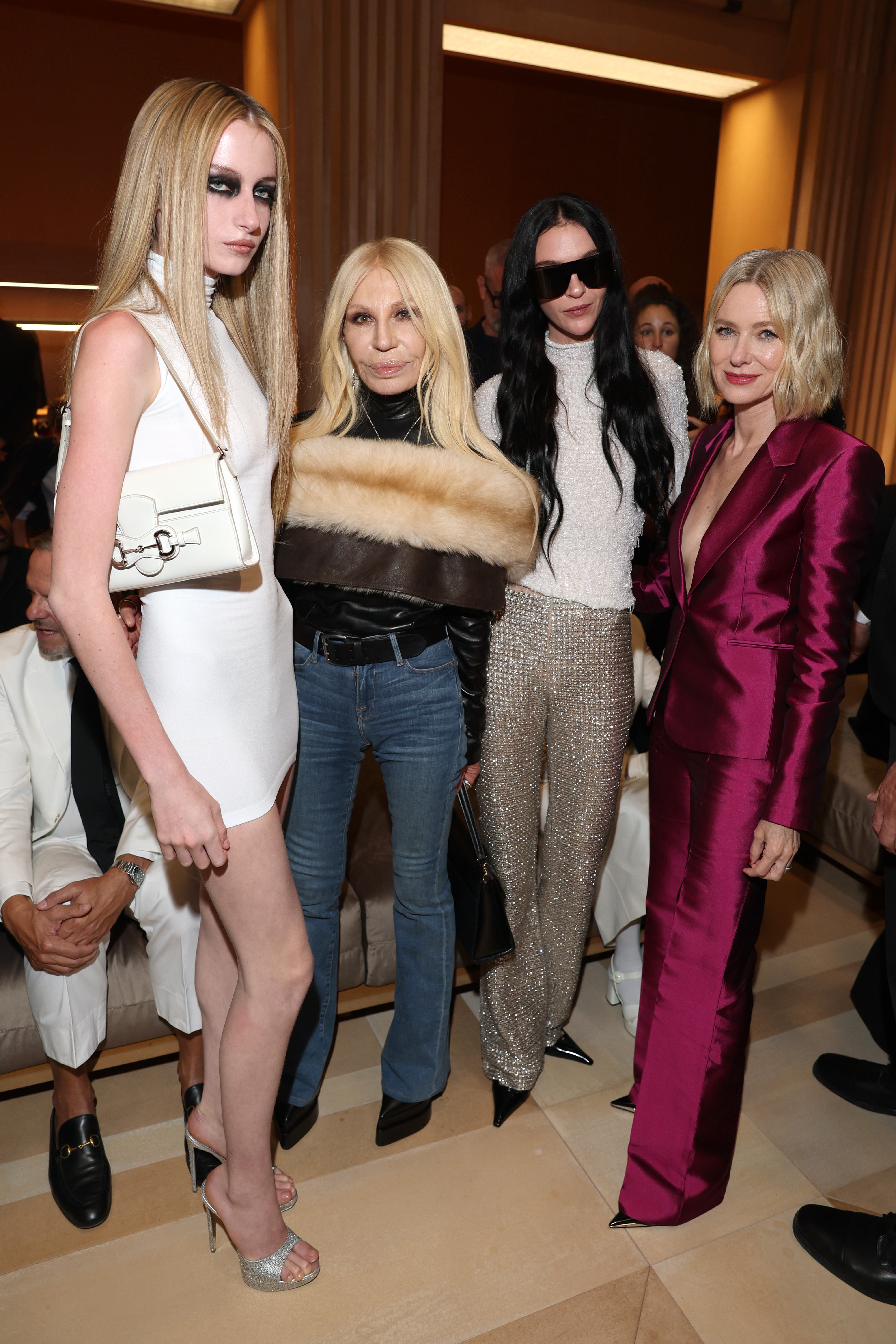 Kai Schreiber, Donatella Versace, Mariacarla Boscono, and Naomi Watts gathered for a star-studded group portrait at the Gucci The Store Show during Milan Fashion Week Womenswear Spring/Summer 2027 at Allianz MiCo on September 25, 2026, in Milan, Italy. The fashionable quartet showcased contrasting styles, with Schreiber in a white sleeveless minidress and silver platform heels, Versace in casual flared denim with a fur-trimmed black leather jacket, Boscono shining in textured metallic trousers with dark sunglasses, and Watts dressed in her sleek magenta satin suit. | Source: Getty Images