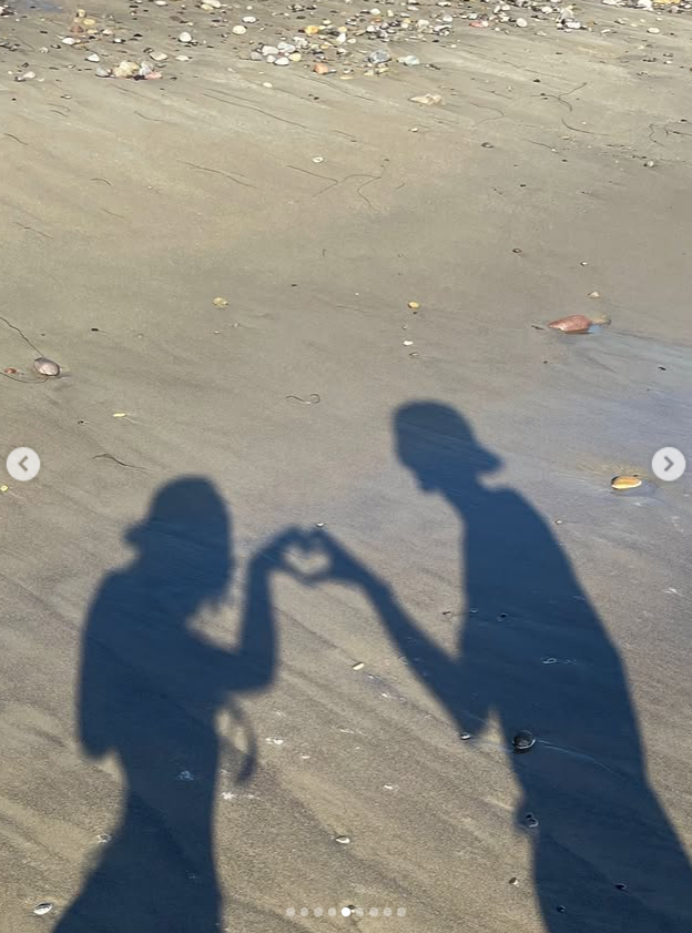 The shadows of Wood and Gerber stretch across the sand as their hands meet to form a heart. The image was another quiet moment Wood chose to include in her remembrance of Gerber. | Source: Instagram/lexiwood