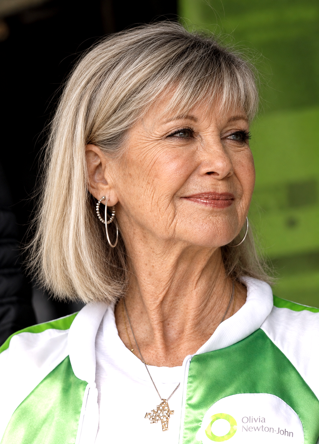 AI-generated impression. At an imagined 75, Olivia appears with subtly aged features while retaining the blond hair and gentle expression fans knew so well. The green-and-white clothing also creates an inadvertent visual echo of the wellness legacy now associated with her name. | Source: Chat GPT