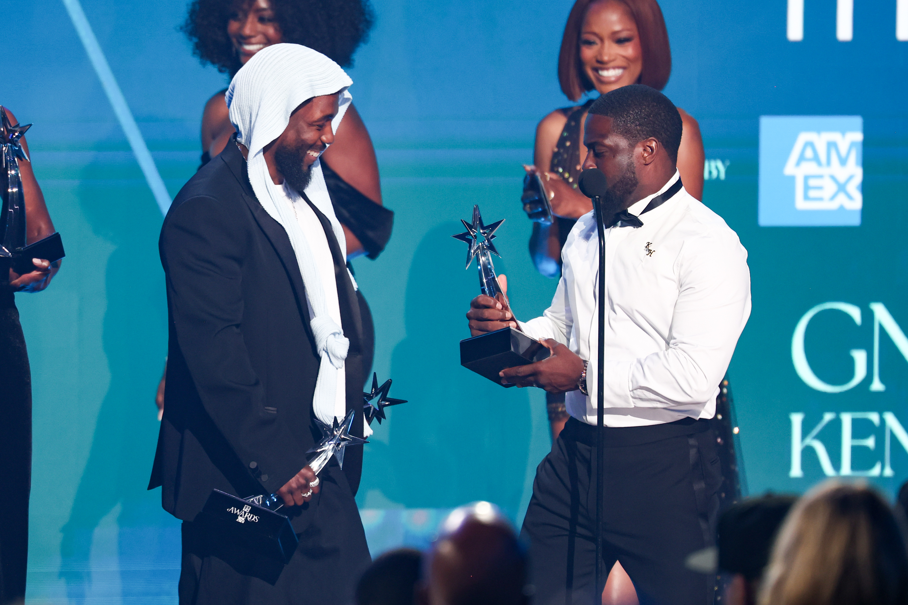 Kendrick Lamar looks on with a smile as Kevin Hart presents him with yet another award during the 2025 BET Awards. The duo's lighthearted banter added a comedic highlight to the rapper's sweep of the night's top honors.