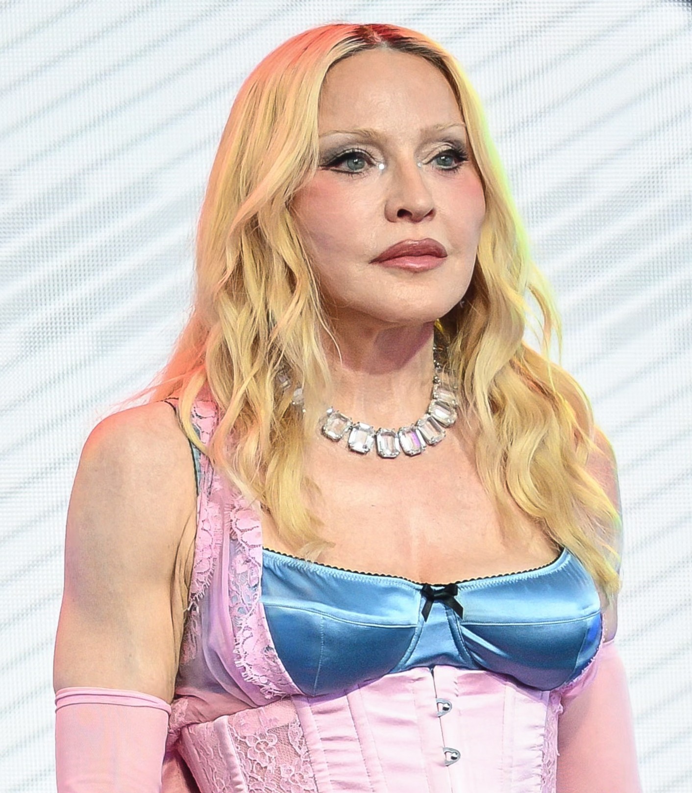 Madonna poses in a pink-and-blue corset-style outfit with long blond hair, pink gloves and a large jeweled necklace. | Source: Chat GPT