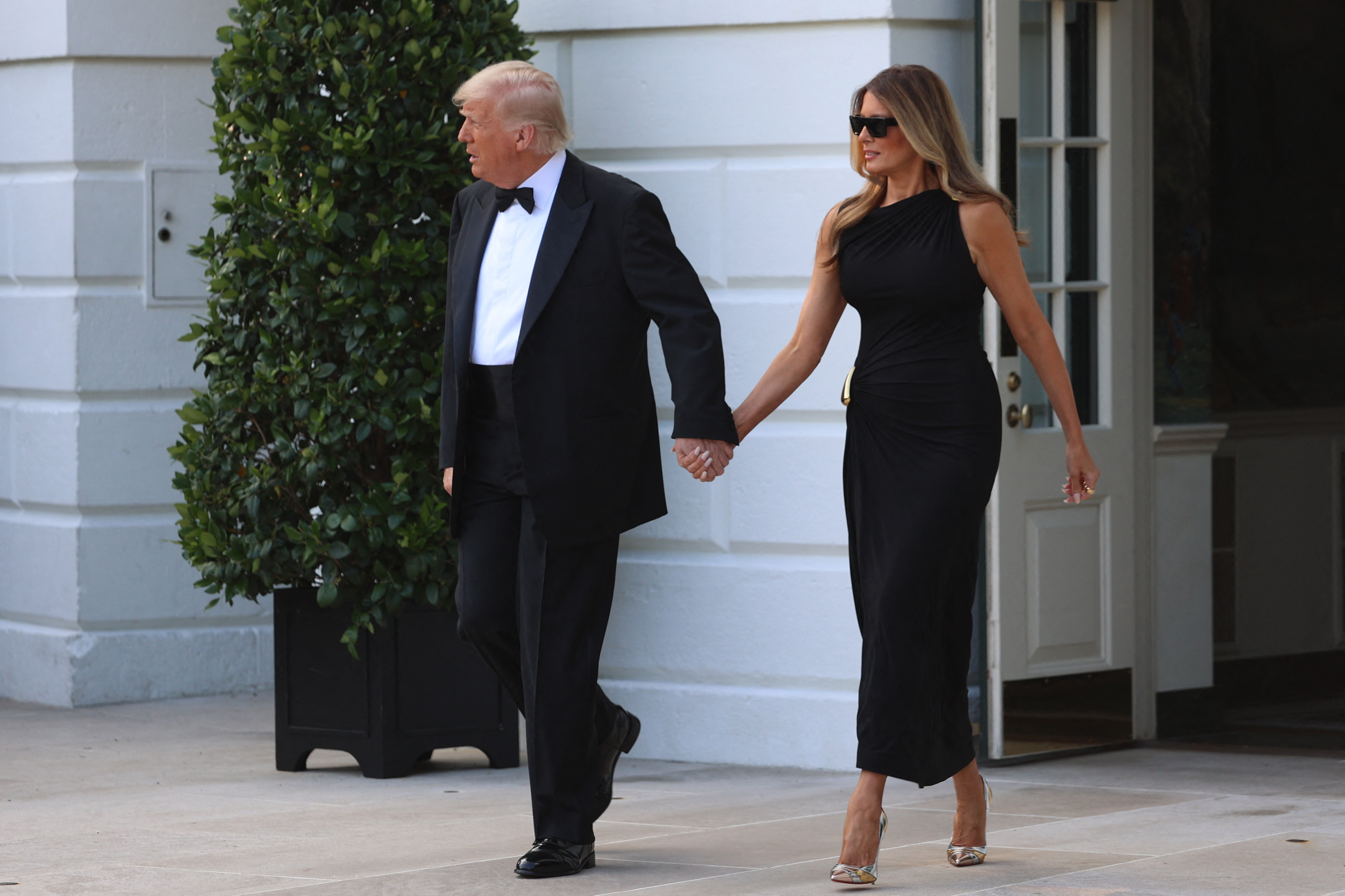 Hand in hand, the president and first lady stride across the White House grounds on June 11, 2025, offering a composed presence in contrasting formalwear ahead of their evening event.
