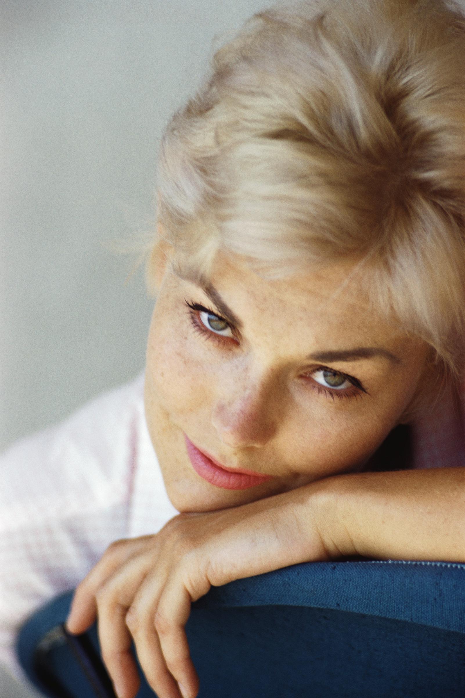 Kim Novak leans her head against the back of a chair in a close-up portrait, her blonde hair swept back and her gaze directed toward the camera. | Source: Getty Images