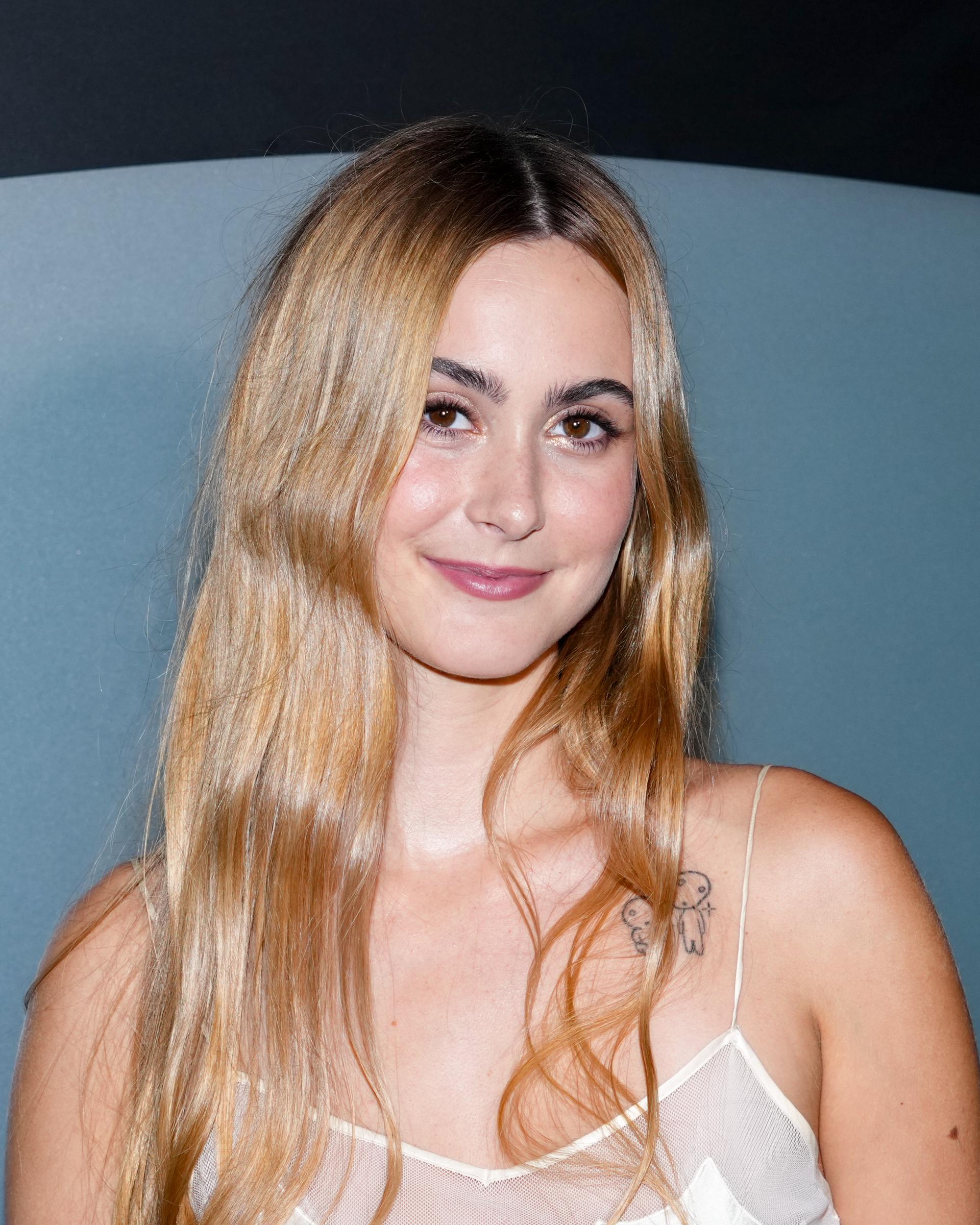 The close-up highlights Coco’s softly waved blonde hair and understated makeup, while the framing draws attention to the small tattoo visible near her left shoulder. Her subtle smile gives the portrait a relaxed feel, offering a more detailed look at the NYFW appearance that later fueled the online conversation about her resemblance to her parents. | Source: Getty Images