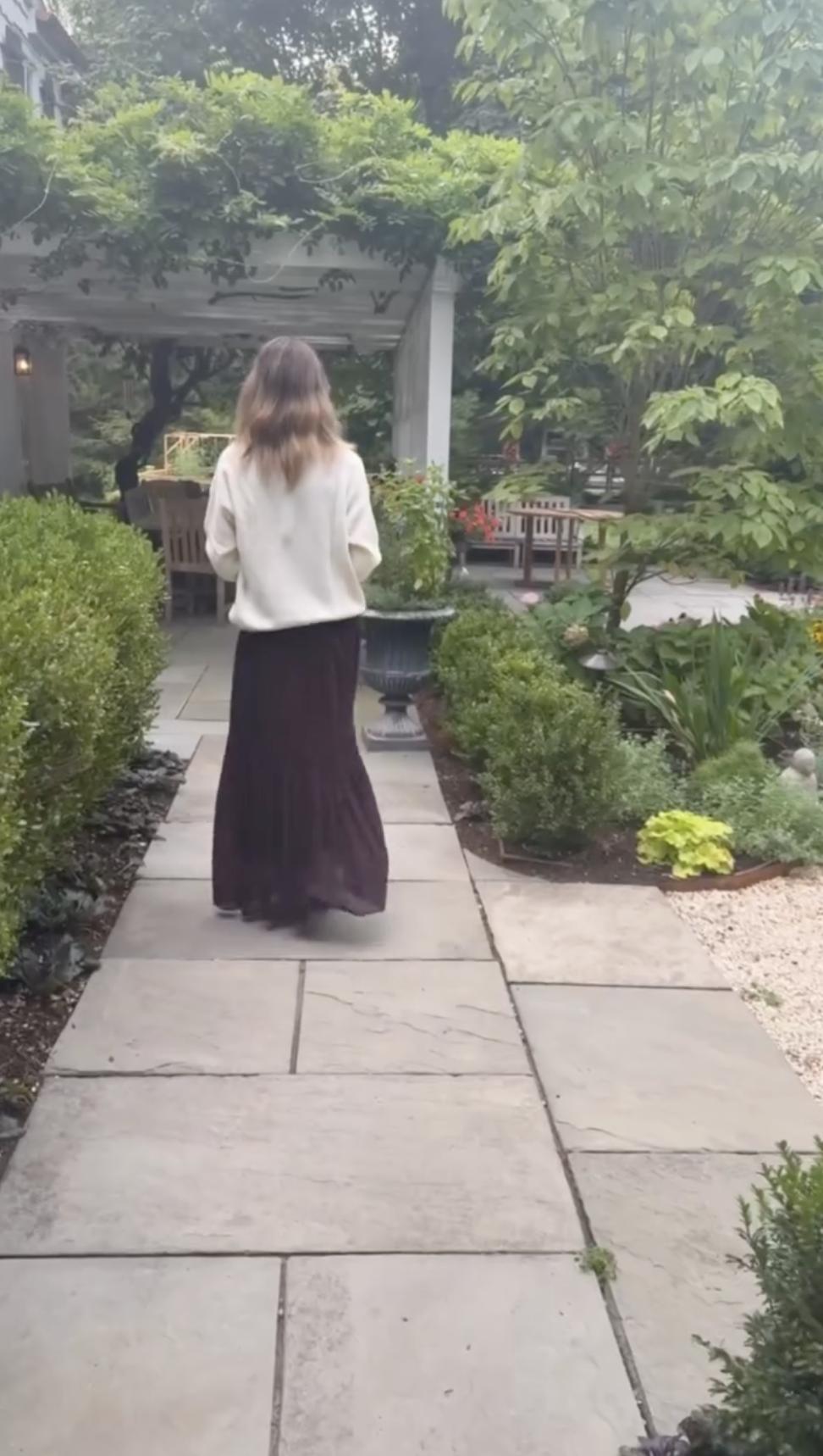 lejandra Silva walks along a stone garden path lined with manicured hedges and flowering plants at the family's home in Spain. | Source: Instagram/alejandragere