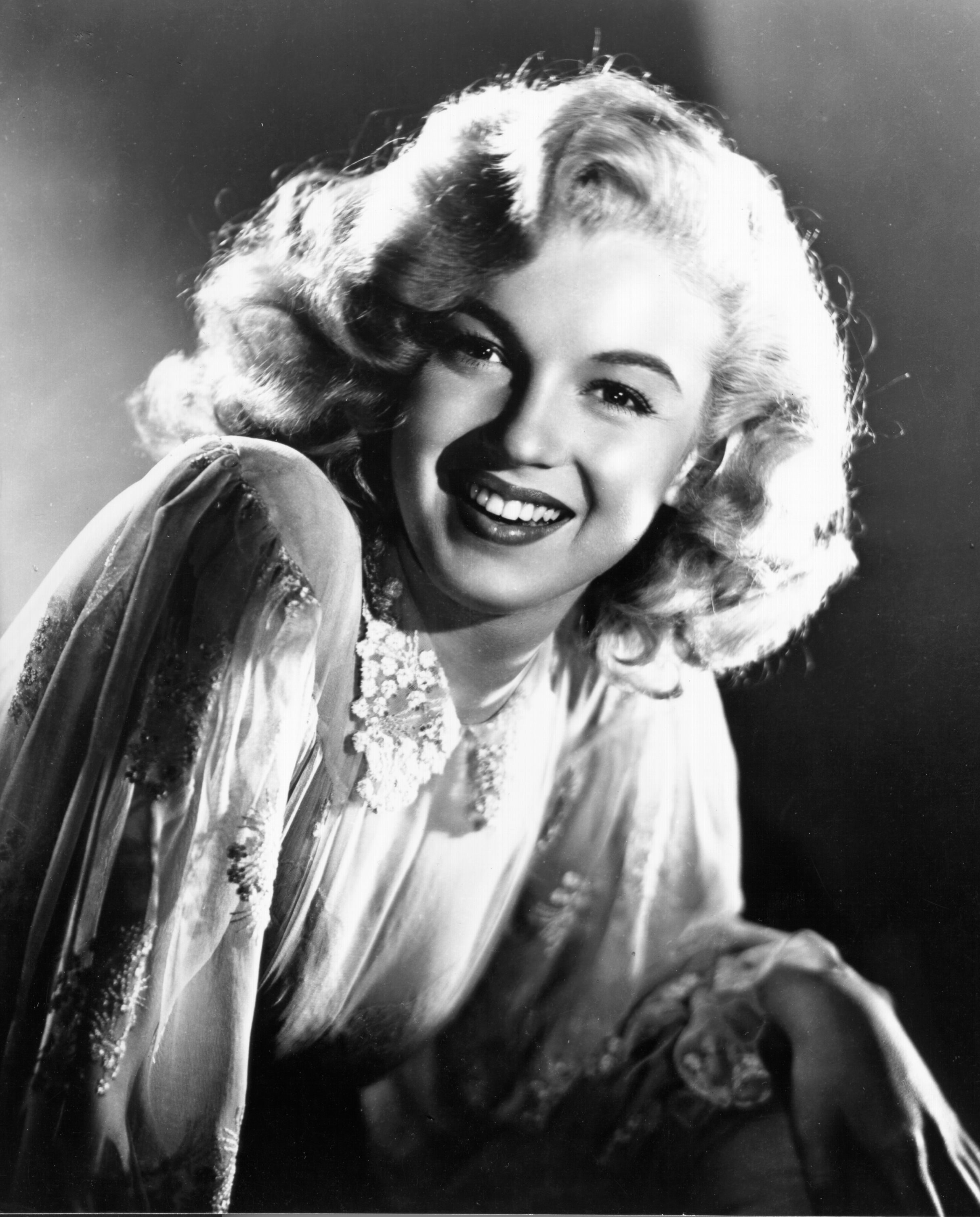 Marilyn Monroe poses for a studio portrait, leaning slightly forward under controlled studio lighting | Source: Getty Images